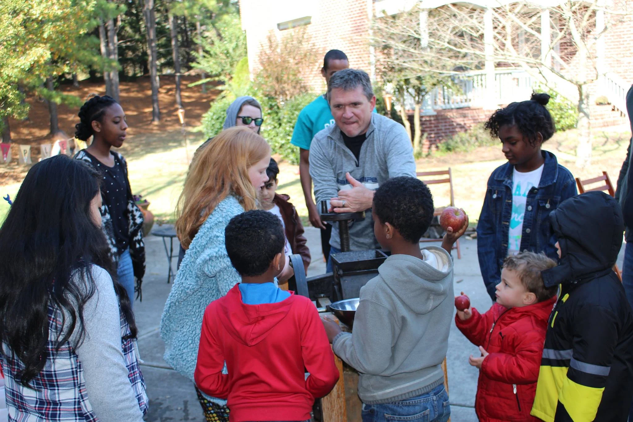 Scott teaching children how to turn the cider press