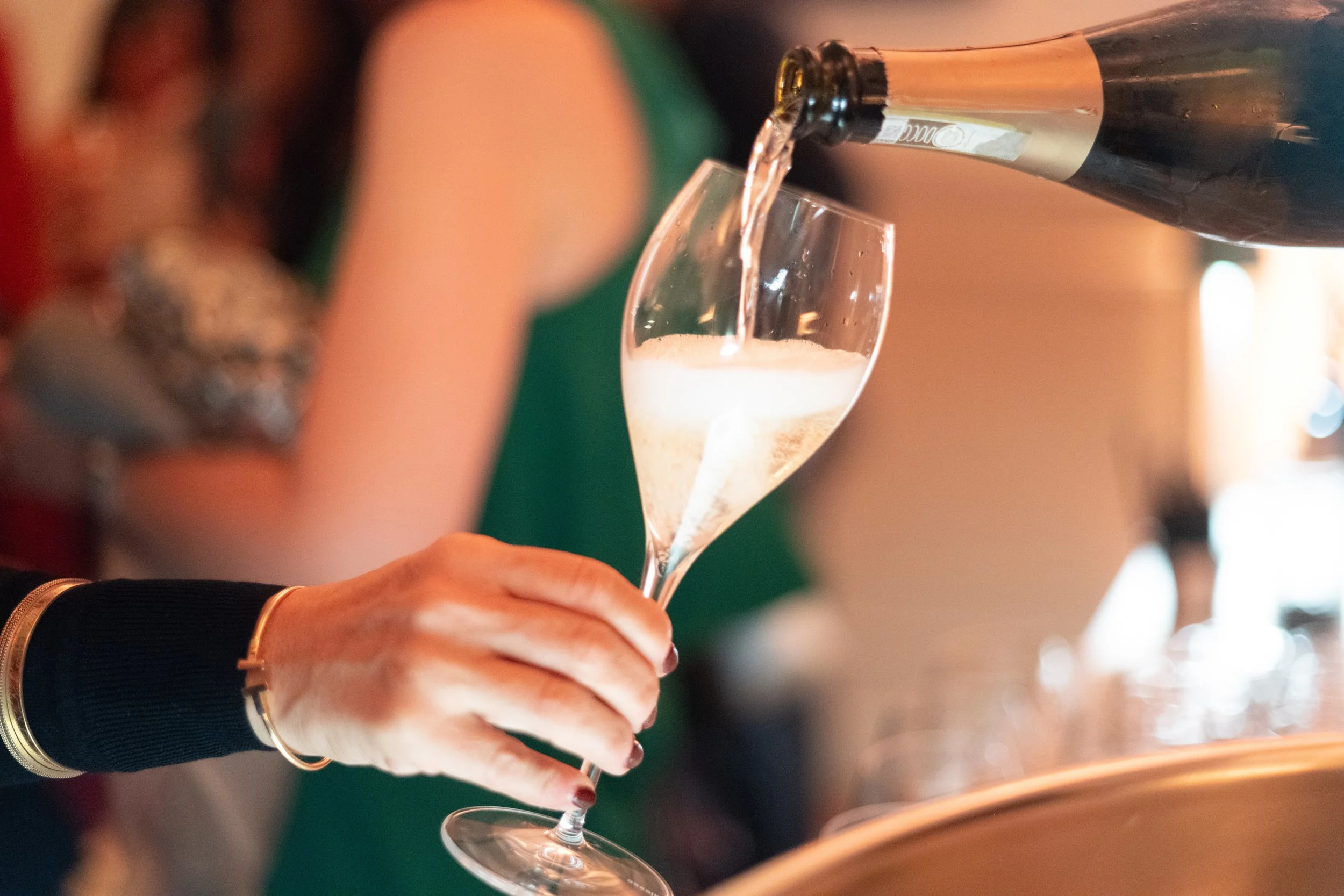 A person pouring champagne into a flute glass at a celebration or party.
