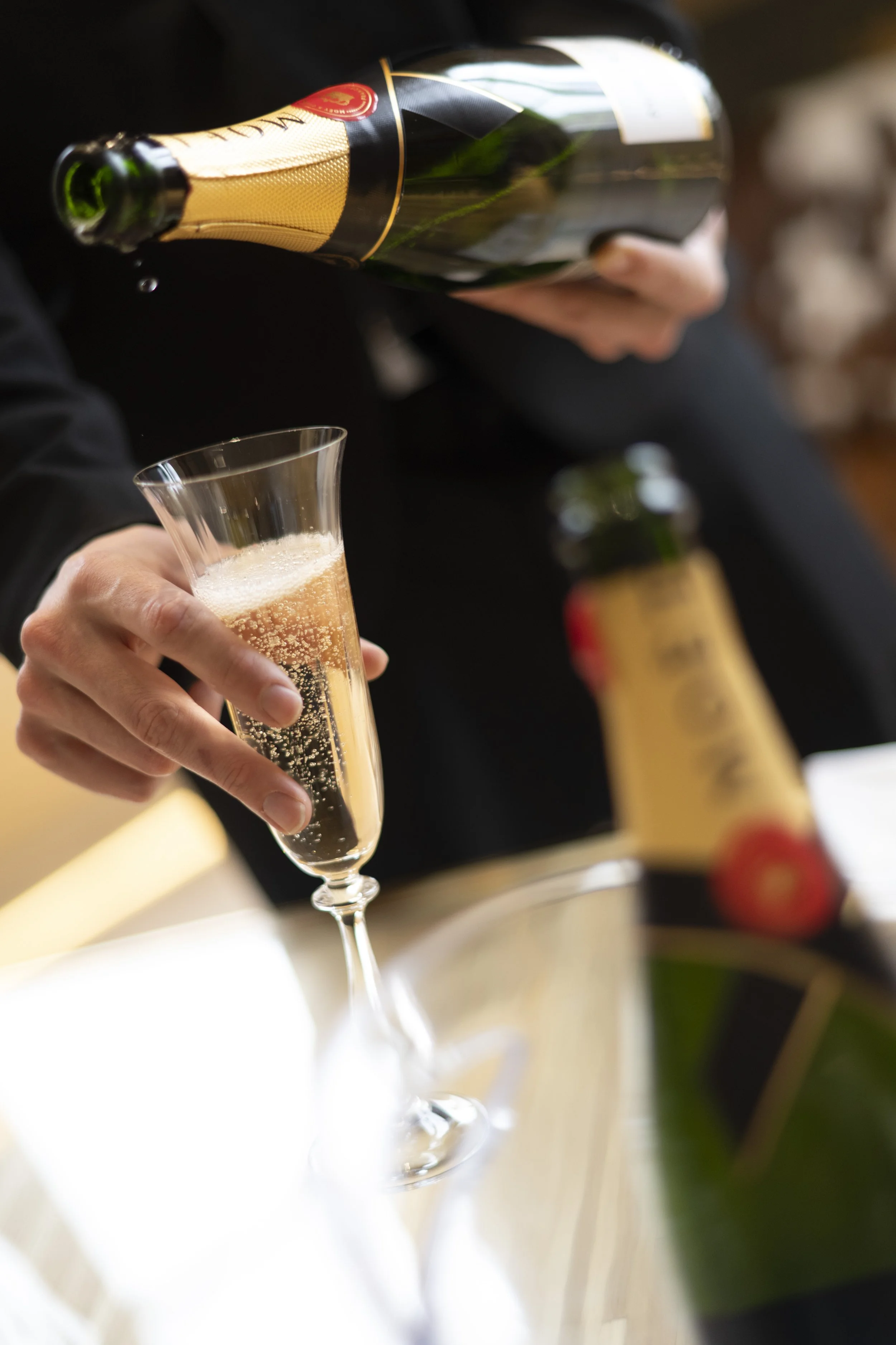 Person pouring champagne into a flute.