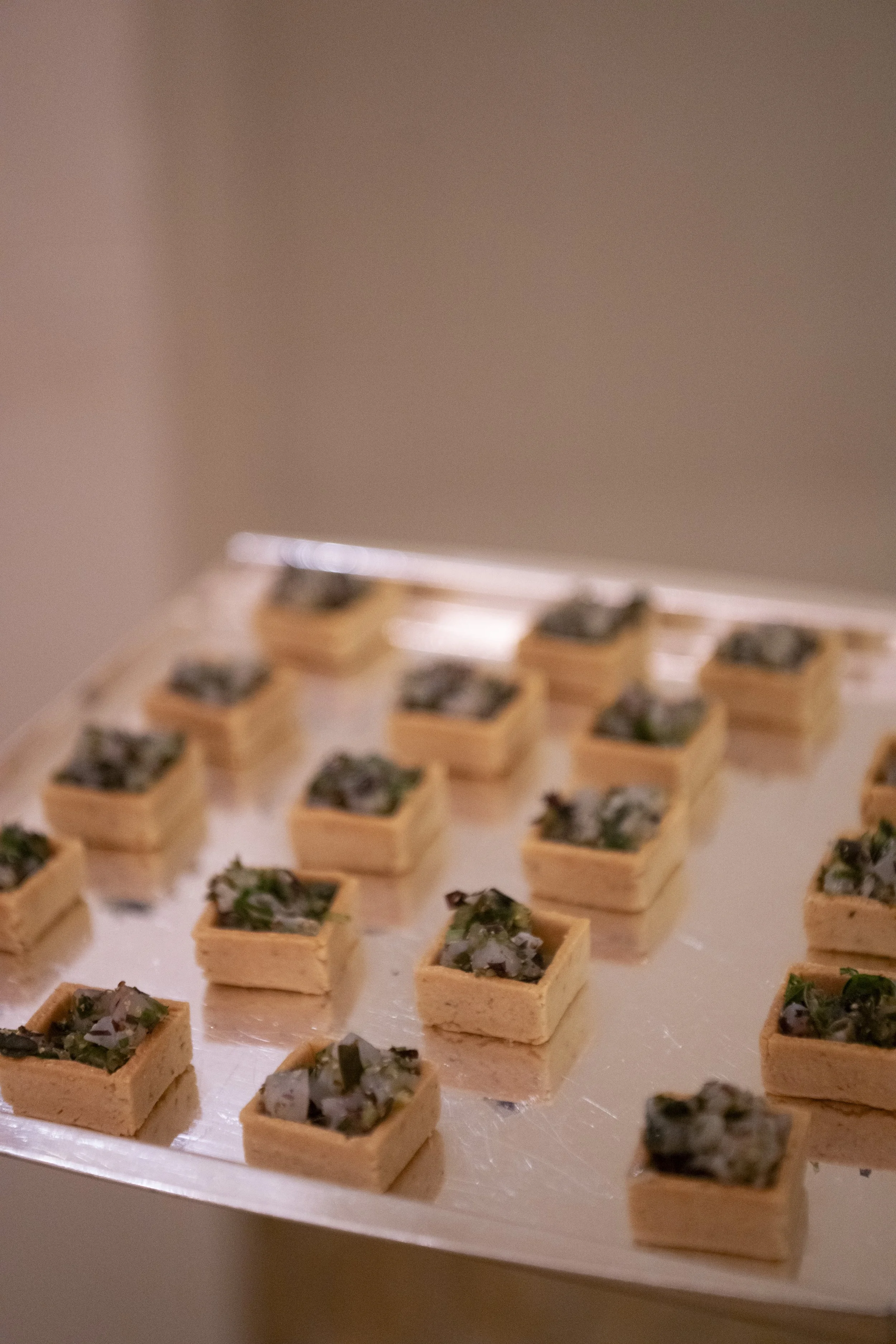 Small wooden trays filled with crushed dark green and grayish stones, arranged on a white surface.