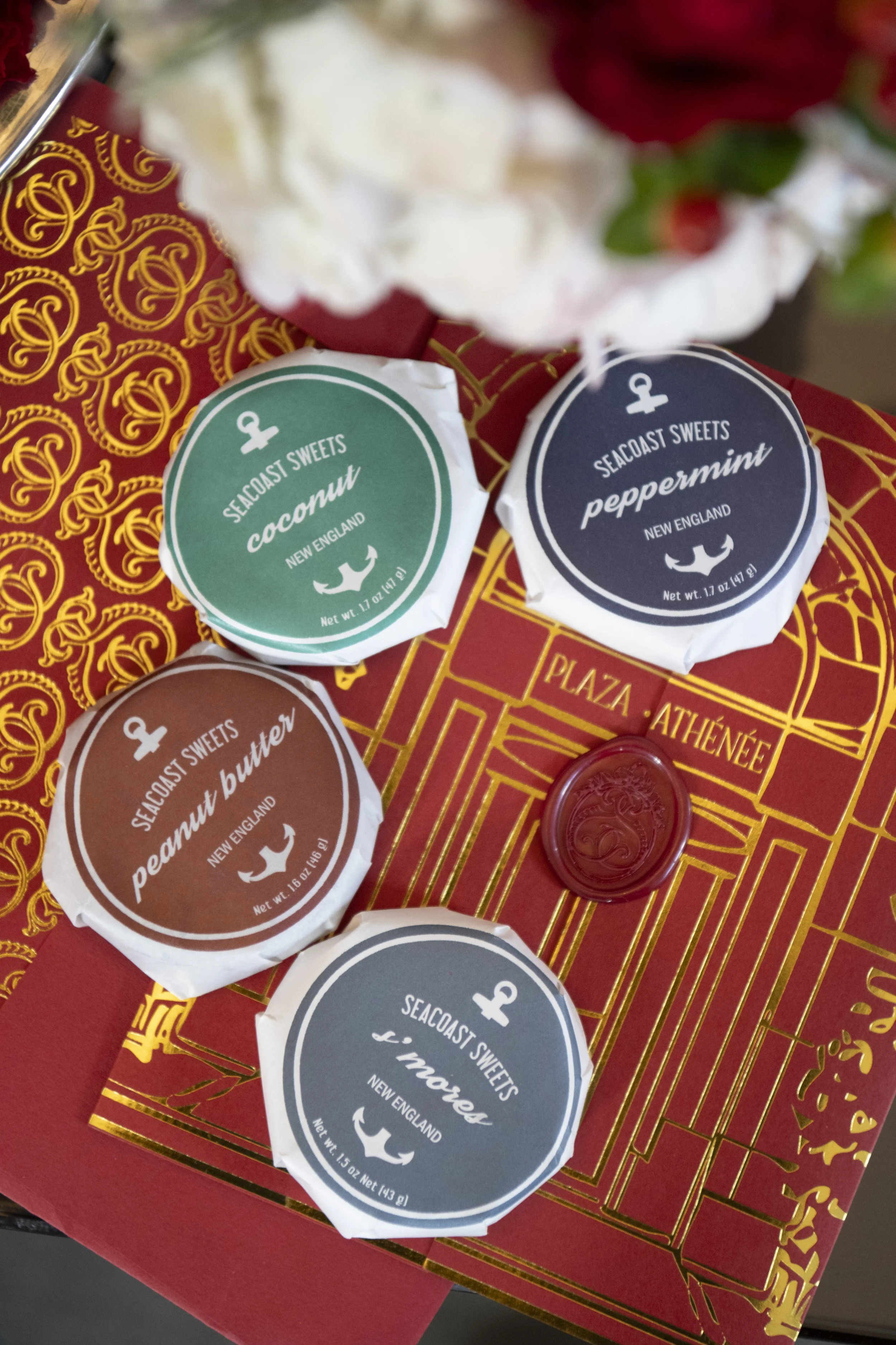 Photo of assorted Seacoast Sweets candies from New England, including coconut, peppermint, peanut butter, and taffy flavors, placed on a decorative red and gold box.