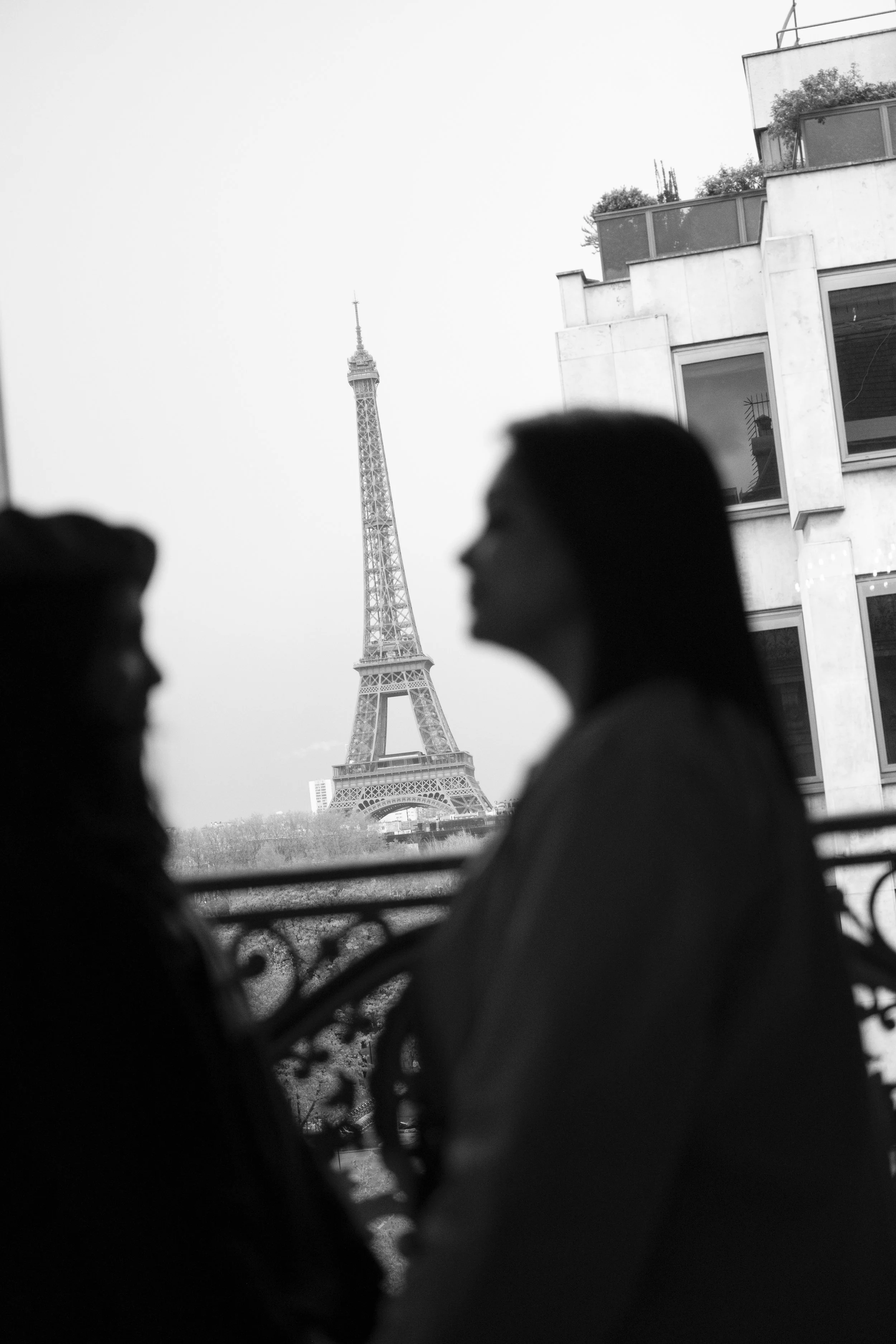 Silhouettes of two people facing each other with the Eiffel Tower in the background, viewed through a window.