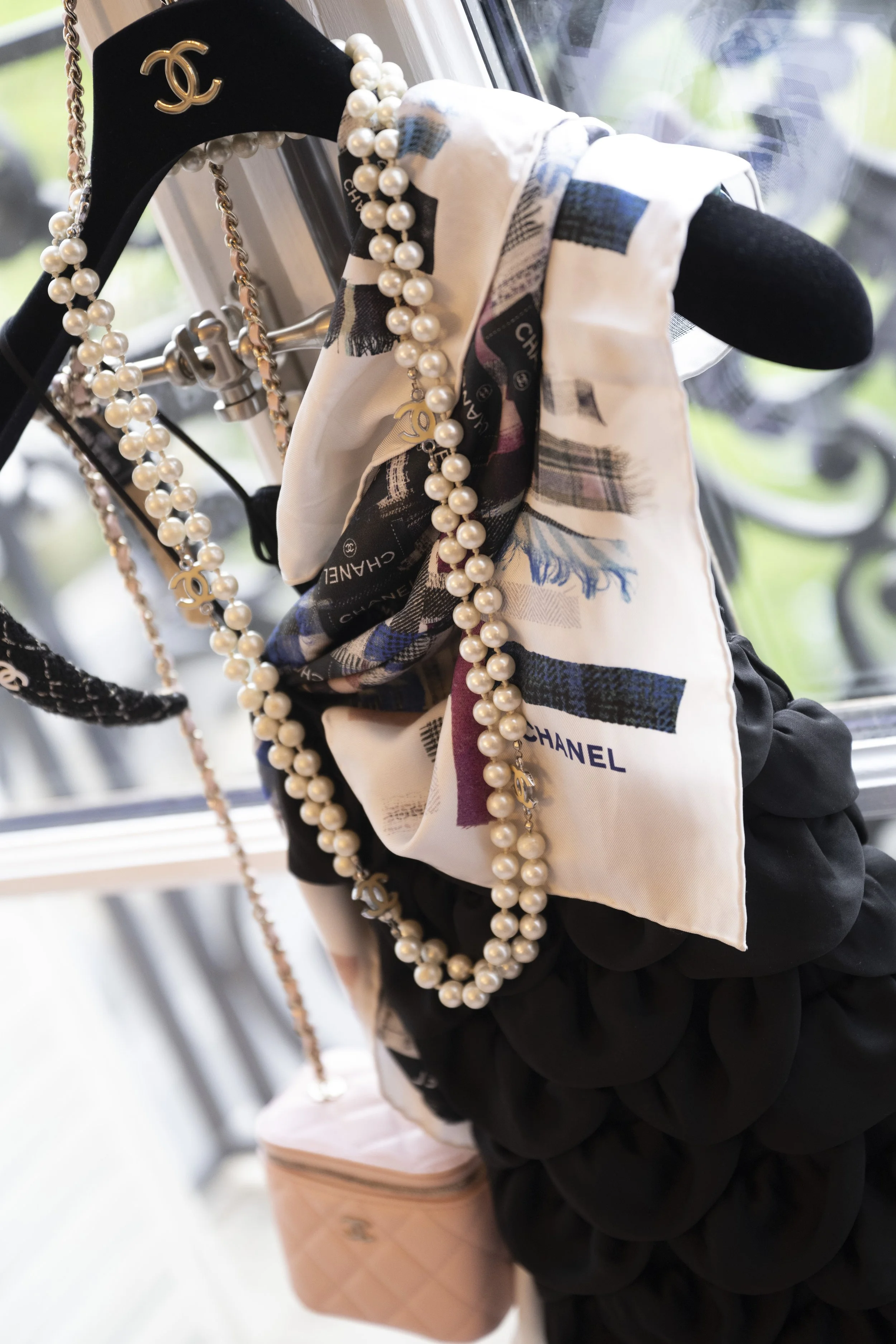 Display of handbags, jewelry, and scarves on an elegant black and beige stand at a boutique or store.