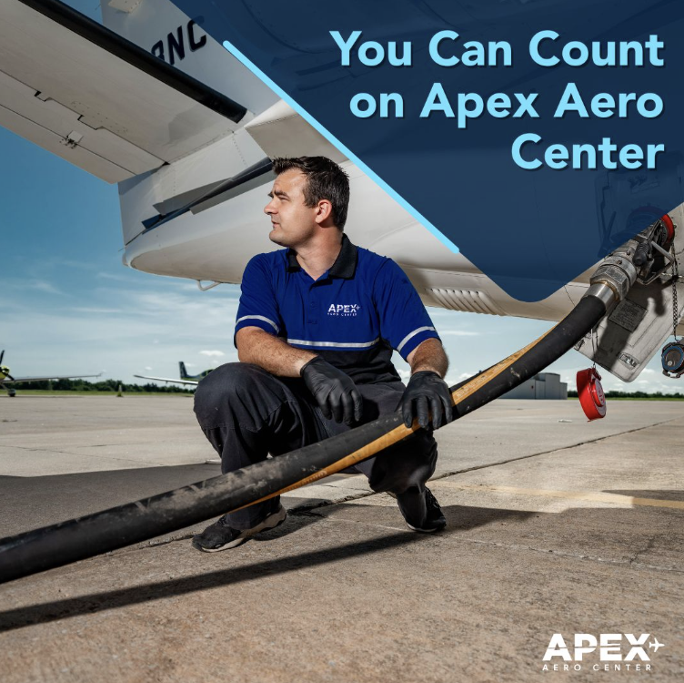 Man crouching down holding the fuel line to an airplane.