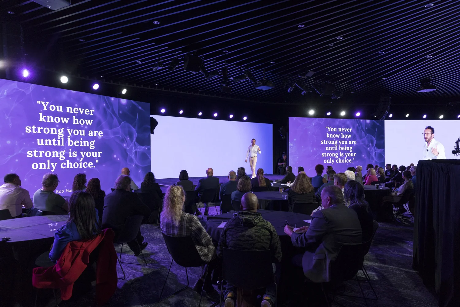 Dr. Adi Jaffe speaking on a keynote stage in front of a large audience