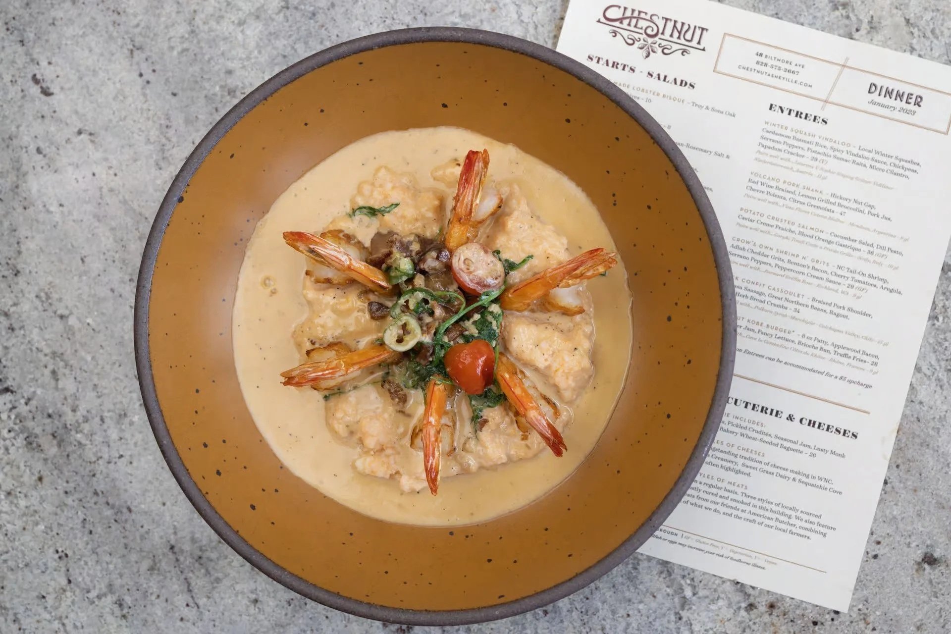 Shrimp and grits on a colorful plate with menu