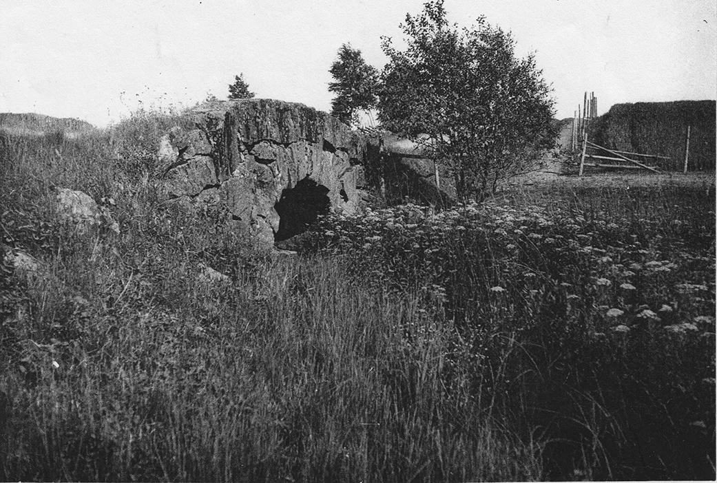 “Bergkvistabrona” fotograferad från väster mot Kivenäbben. Vägen österut i bakgrunden. Bliden tagen före 1930-talet. Då byggdes den om och valvet ersattes med en flat bro. När vägen sedan byggdes 1961 sprängdes den gamla bron bort helt. Samtidigt breddades vägen varvid en del av tomterna från de två stugorna försvann. När bron på bilden byggdes är okänt. Men vägen har alltid haft denna sträckning.