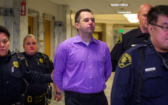 McEnroe being led to the courtroom on the first day of his trial (source: The Seattle Times)