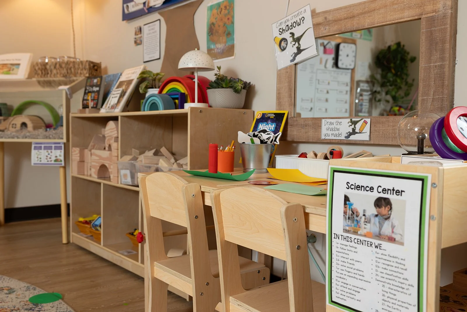 Children's Montessori inspired play and learning area with wooden furniture, colorful crafts, and educational posters.