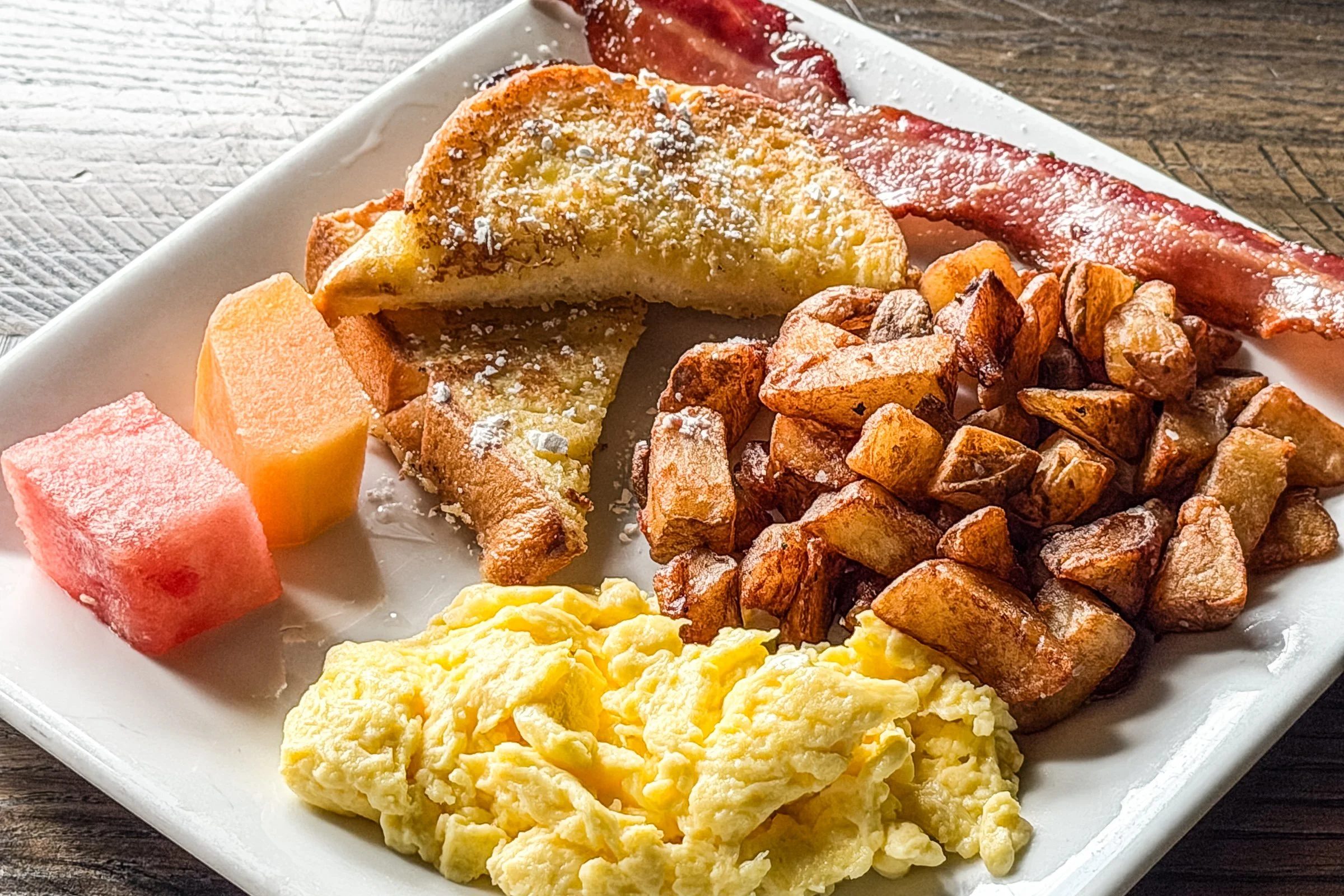 brioche french toast, scrambled eggs, breakfast potatoes, bacon