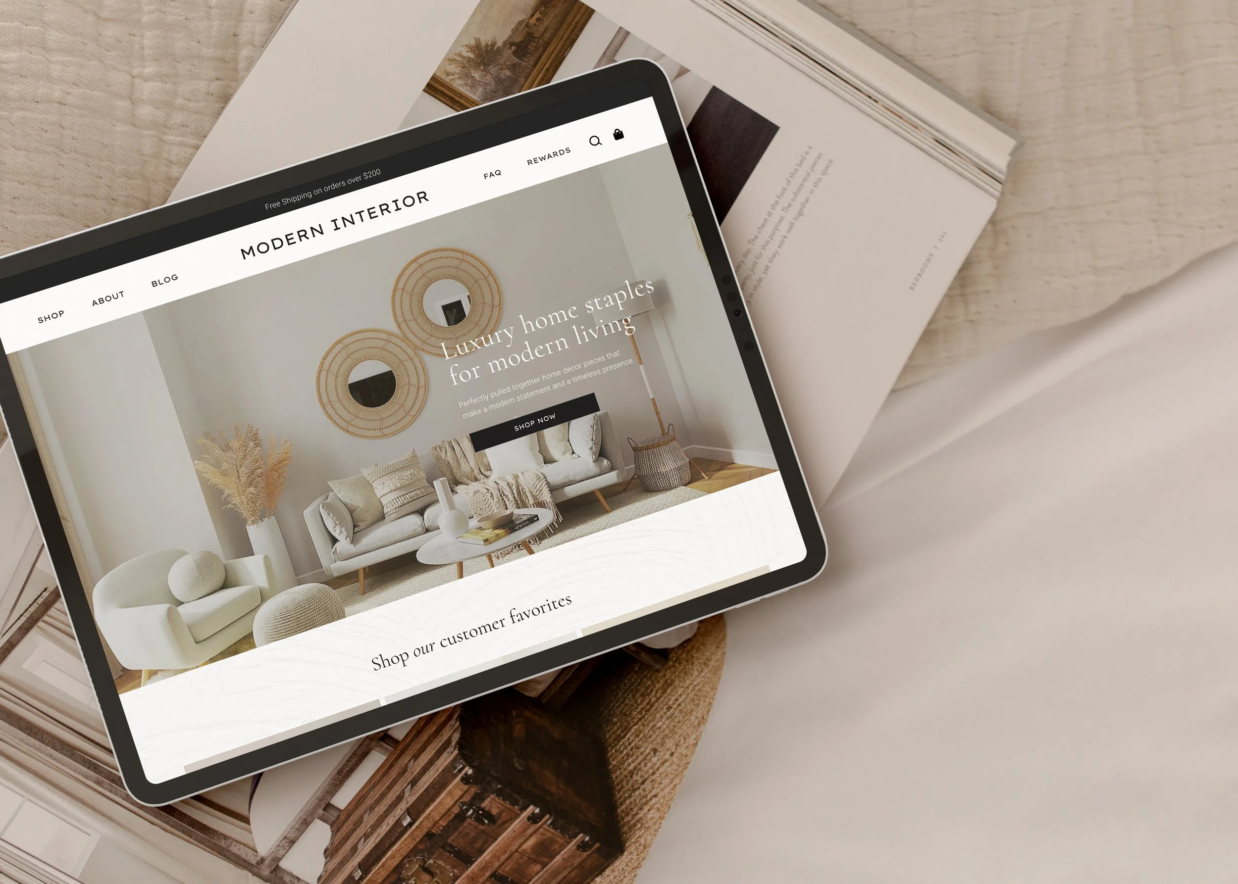 Tablet displaying a modern interior furniture website, paired with open design magazines on a neutral fabric surface.