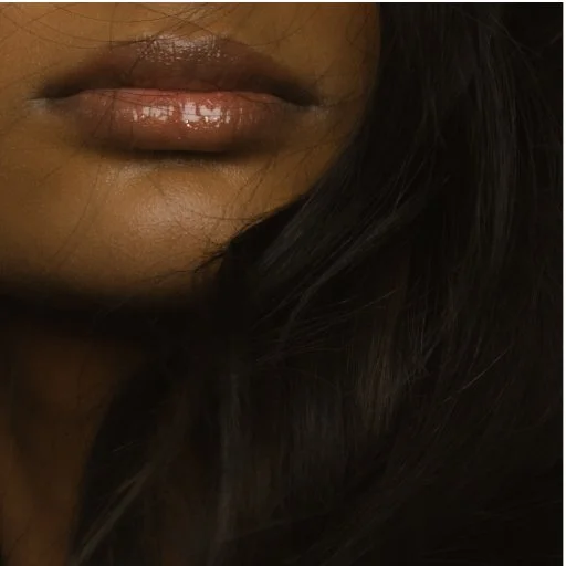 Partial close-up of a person's lips and dark hair.