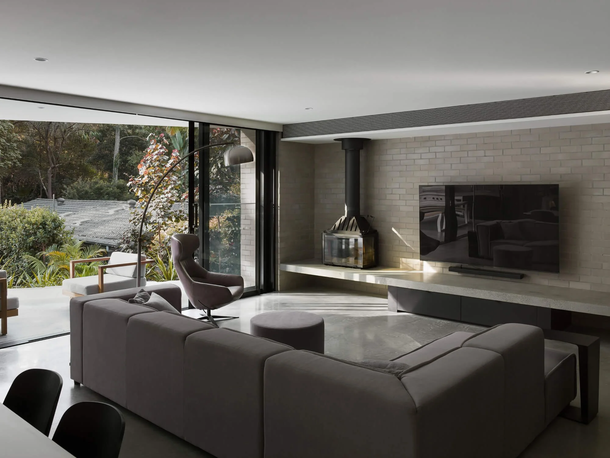 Suspended concrete entertainment bench positioned above flood planning level with black steel fireplace, Pearl Beach NSW