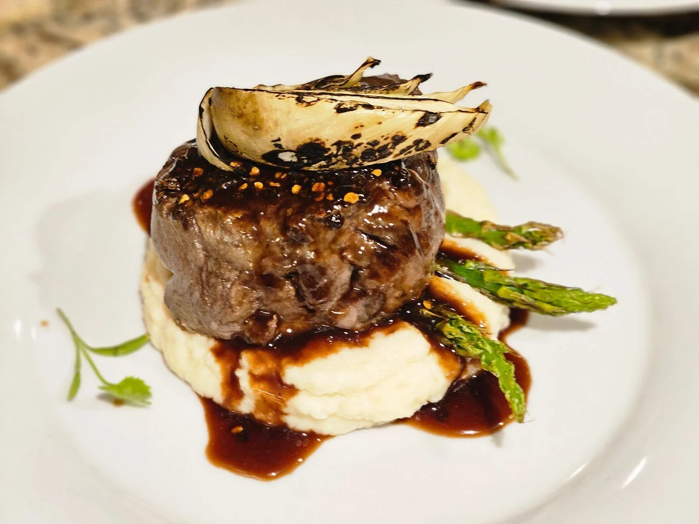 This dish doesn&rsquo;t play around.
Juicy filet mignon, garlic mashed potatoes, roasted asparagus &mdash; all brought together with a deep red wine demi-glace and charred onion crown.

Whether it&rsquo;s Christmas dinner, a corporate party, or NYE a