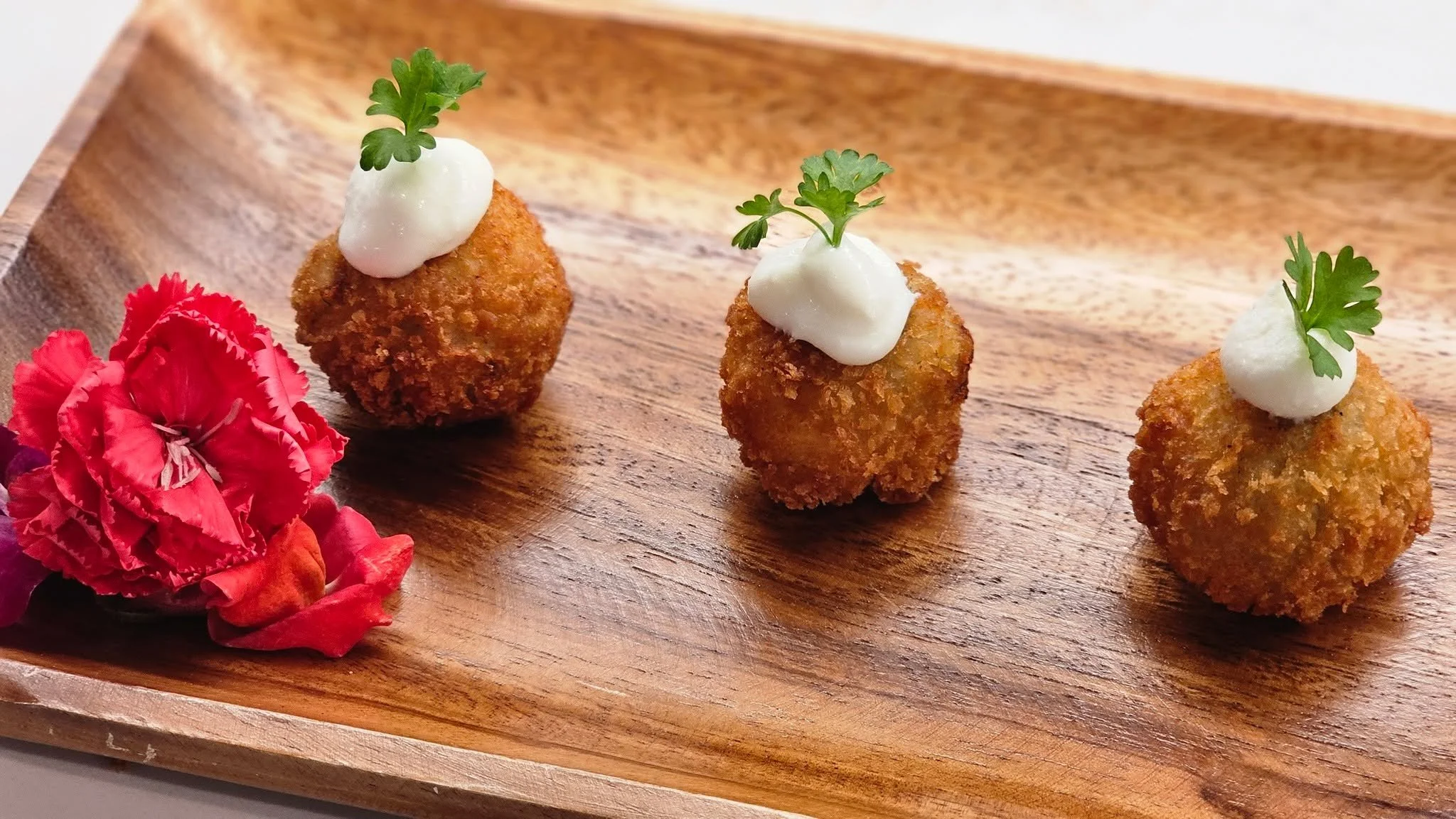 Three little bites. One big impression. 🌸✨
This is what happens when your caterer actually cares &mdash; golden, crispy on the outside, creamy on the inside, topped with a cloud of sauce and a tiny herb crown like they dressed for the occasion.

Bec