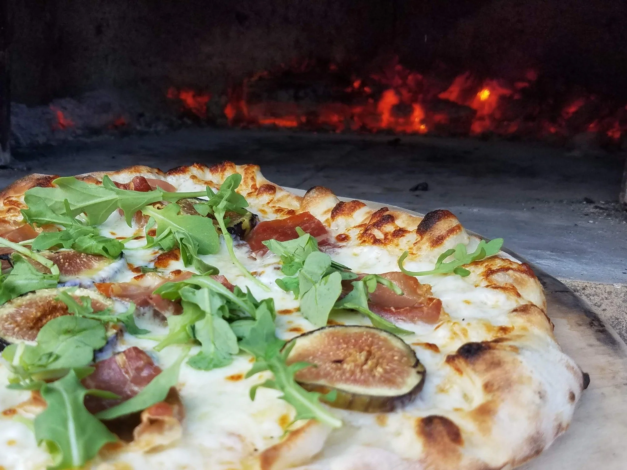 Sweet figs. Salty prosciutto. Creamy cheese. Fresh arugula.

The perfect balance of flavors baked in a wood-fired oven until the crust reaches golden perfection.

One bite and you'll understand why this is a guest favorite.

Fresh ingredients. Artisa