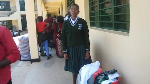 Aline in school uniform and waiting for room assignment.