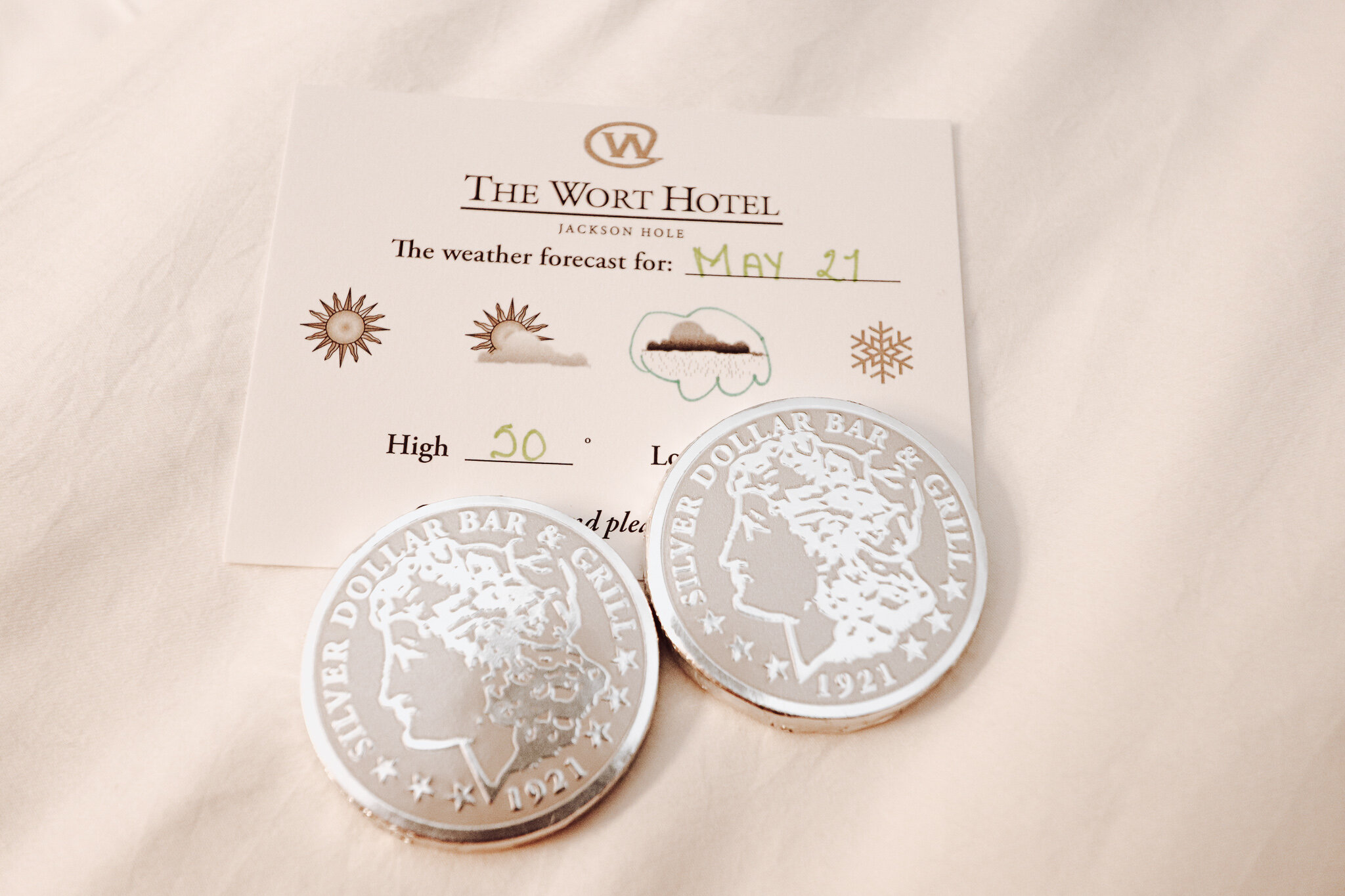  Silver Dollar chocolates are left on the bed with a daily weather report. 