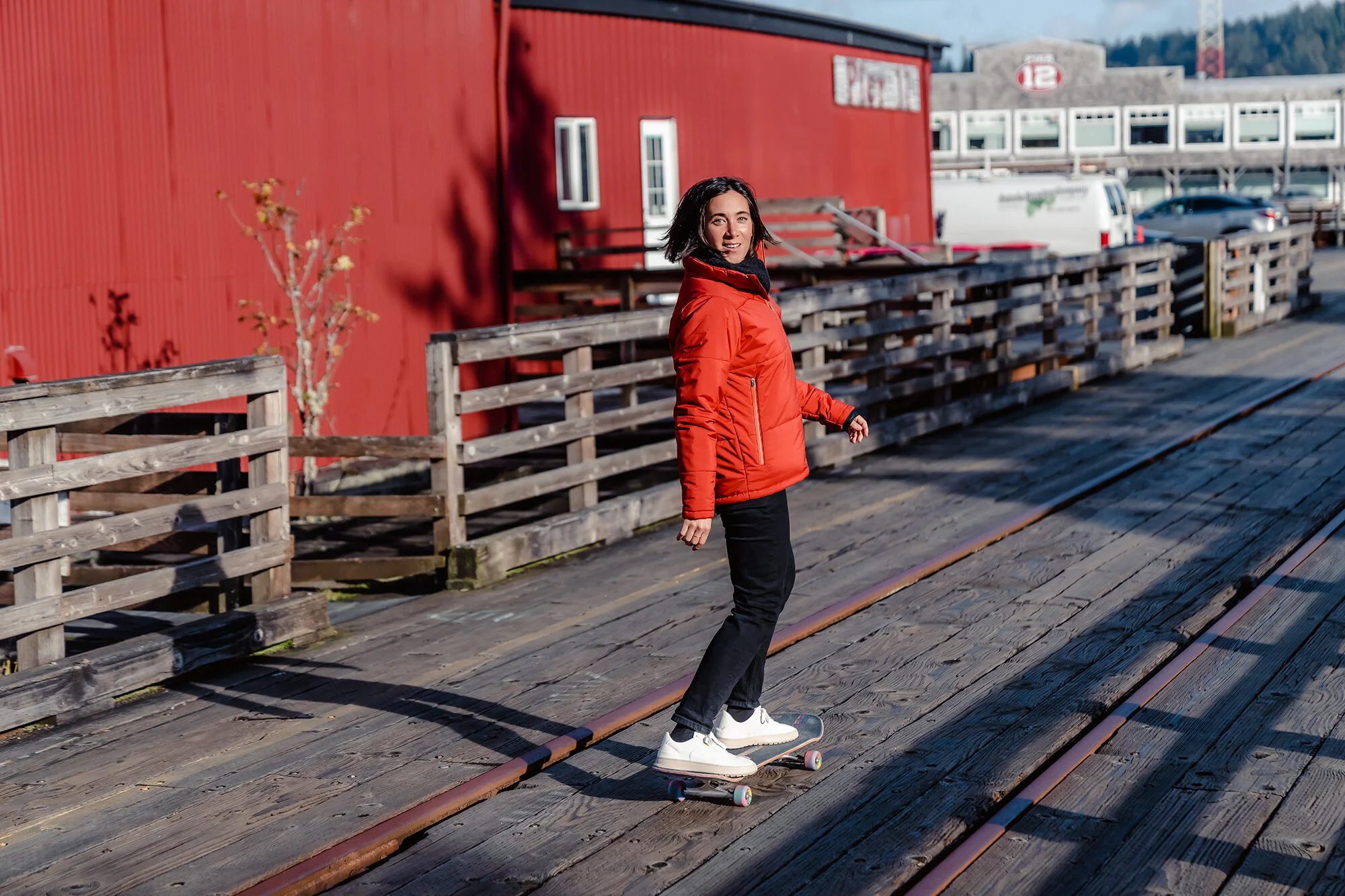 A photo by Mark McInnis of a woman wearing a red Baro Drywear jacket in front of a red building.