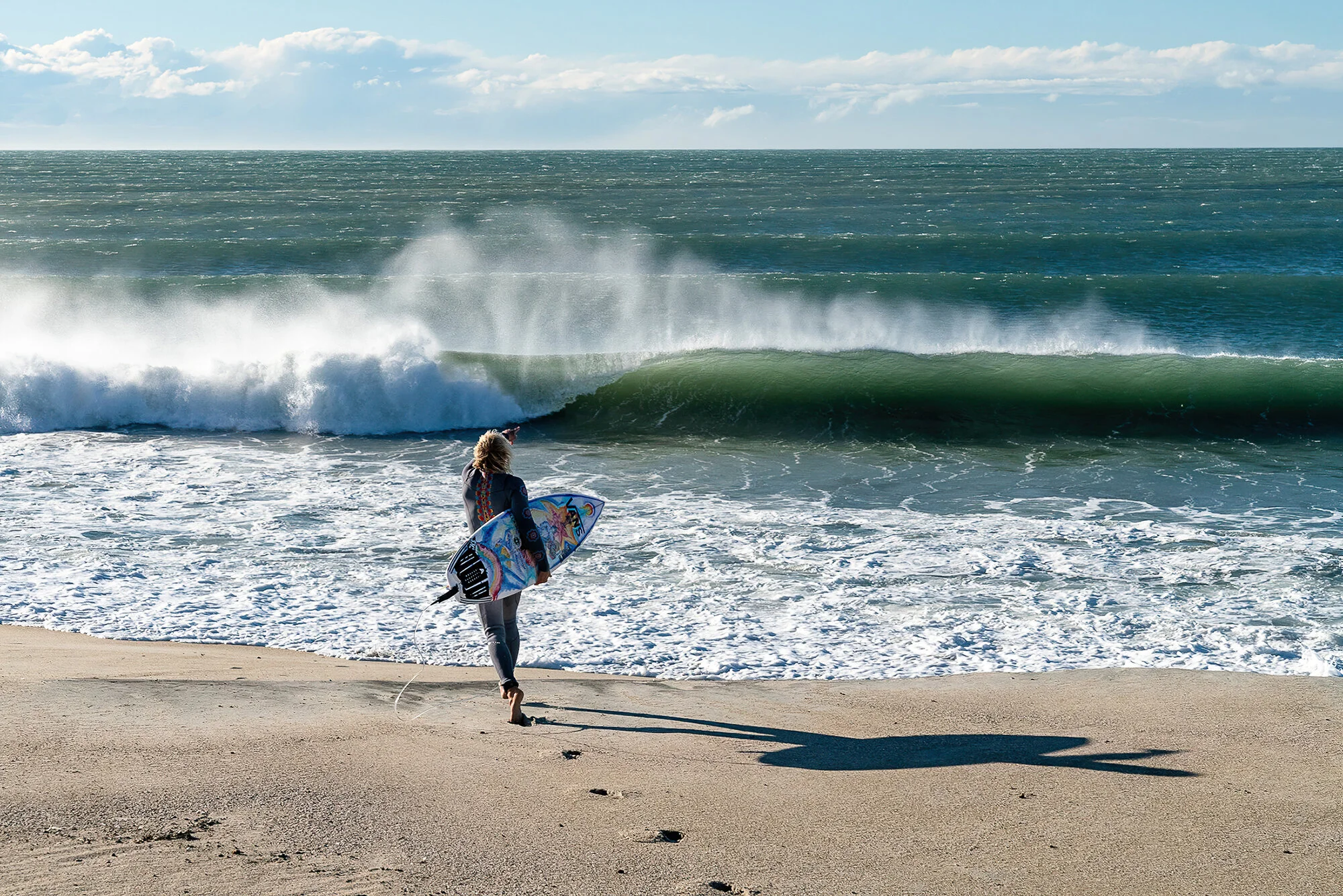 A photo by Mark McInnis of a surfer running into the surf.