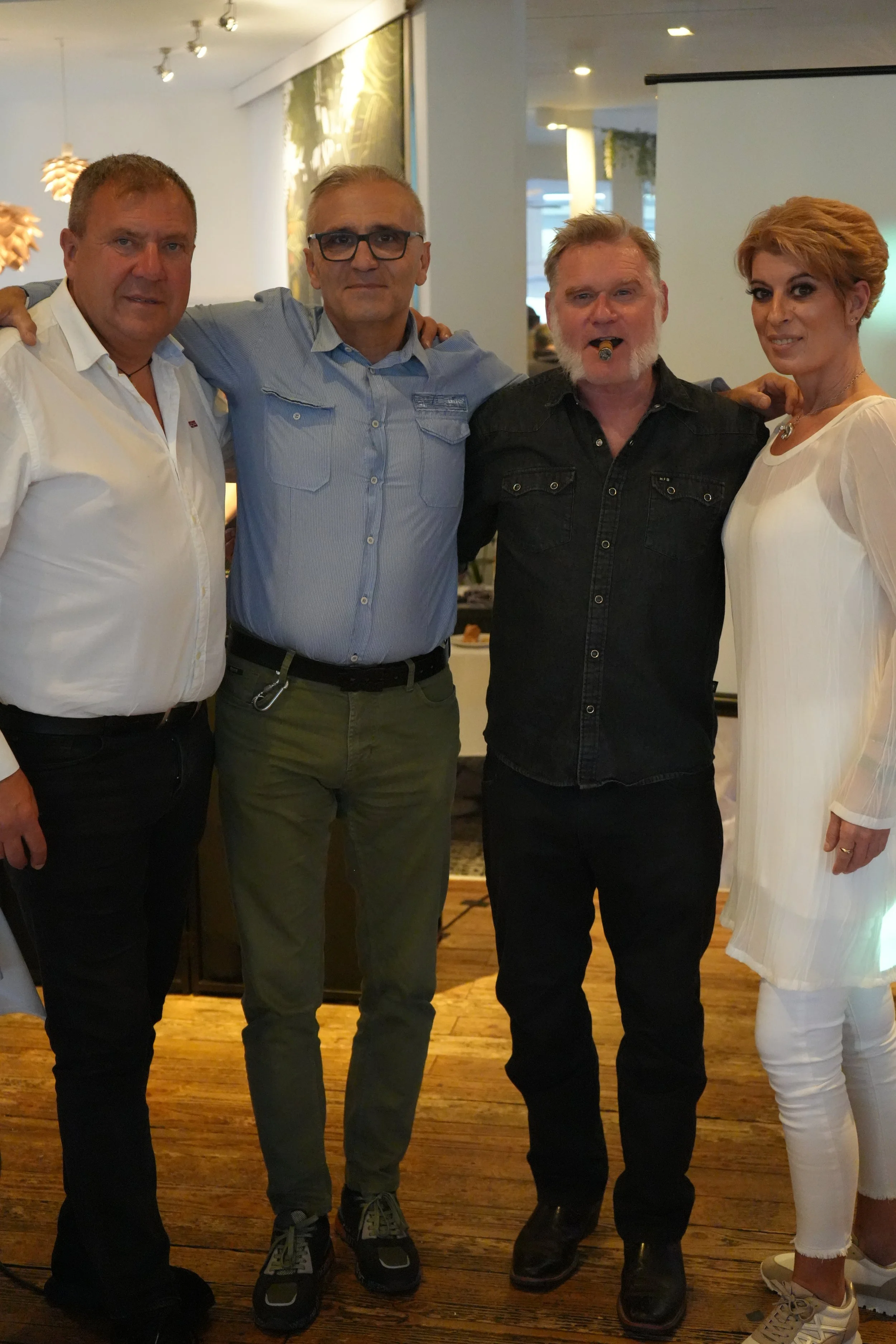 Group of four people standing together indoors, posing for a photo.