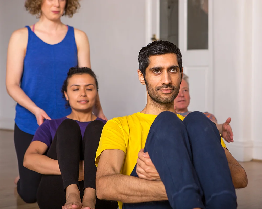 Janine teaches students a balancing yoga posture