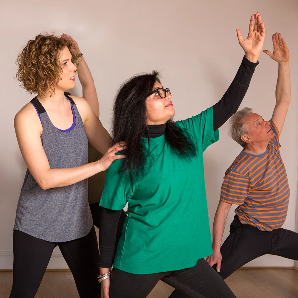 Janine adjusts a student in warrior pose