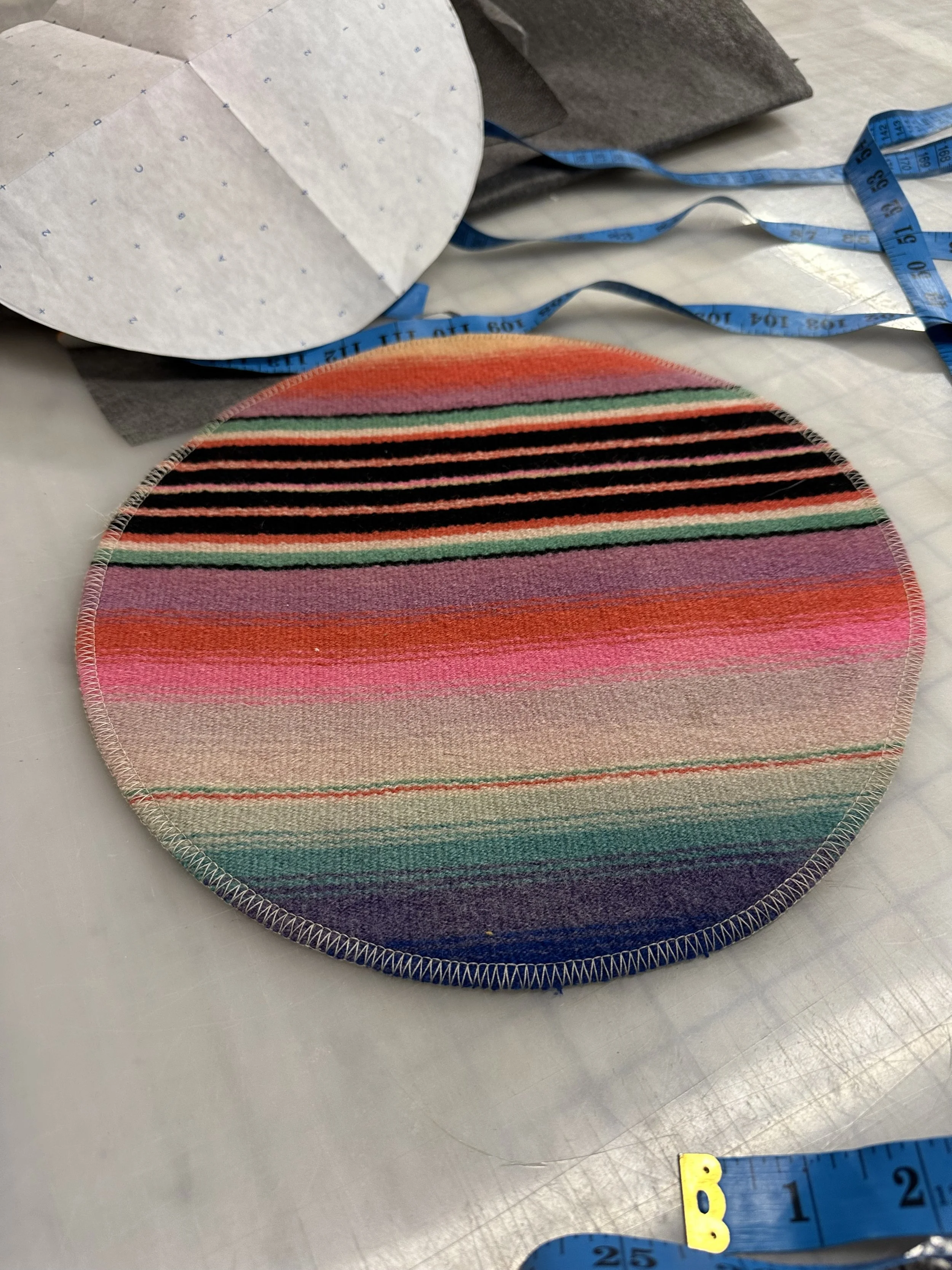 Colorful striped circle fabric, measuring tape and paper pattern pieces on a table.