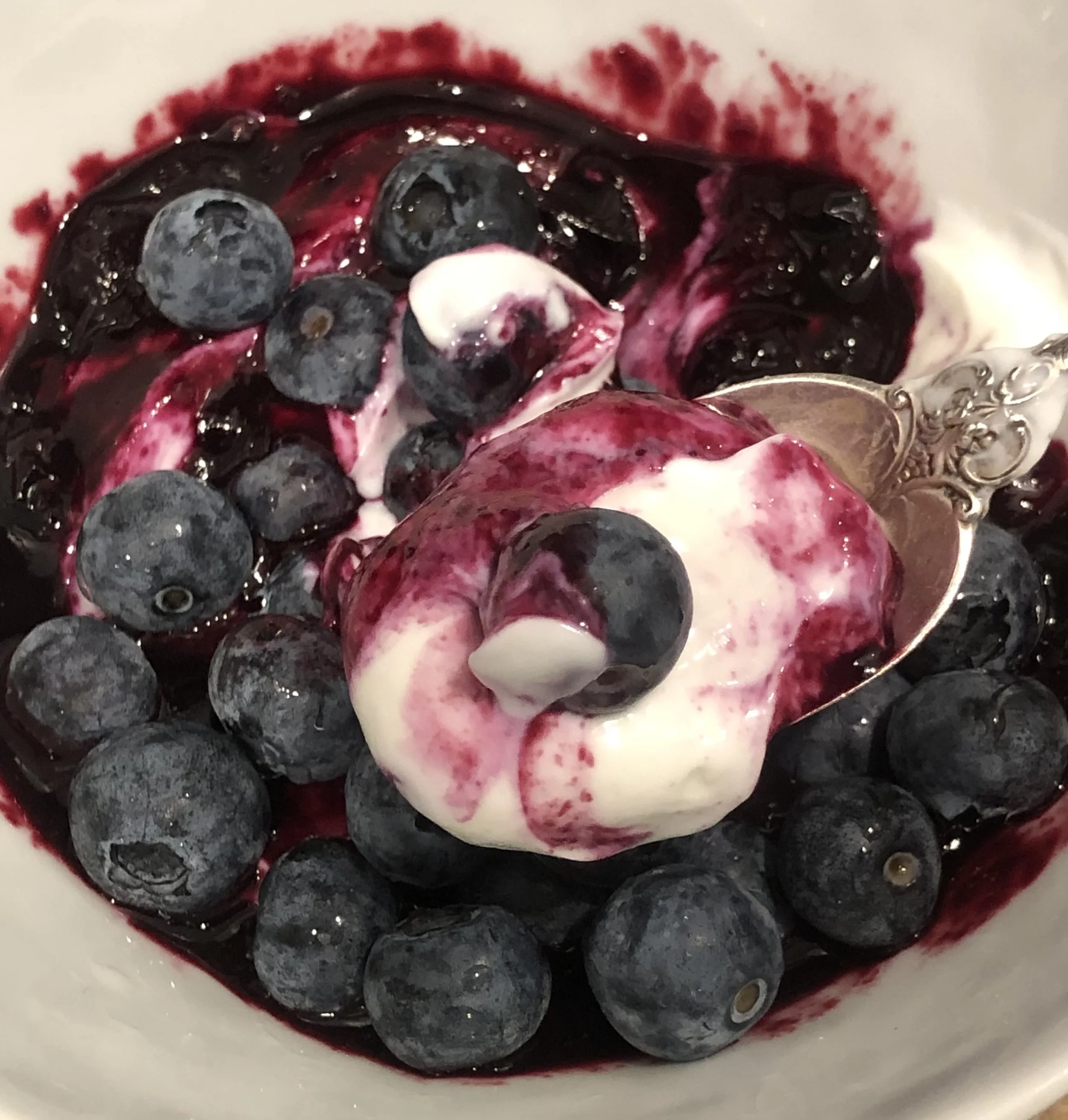 Close-up of blueberries and berry syrup on a white plate.