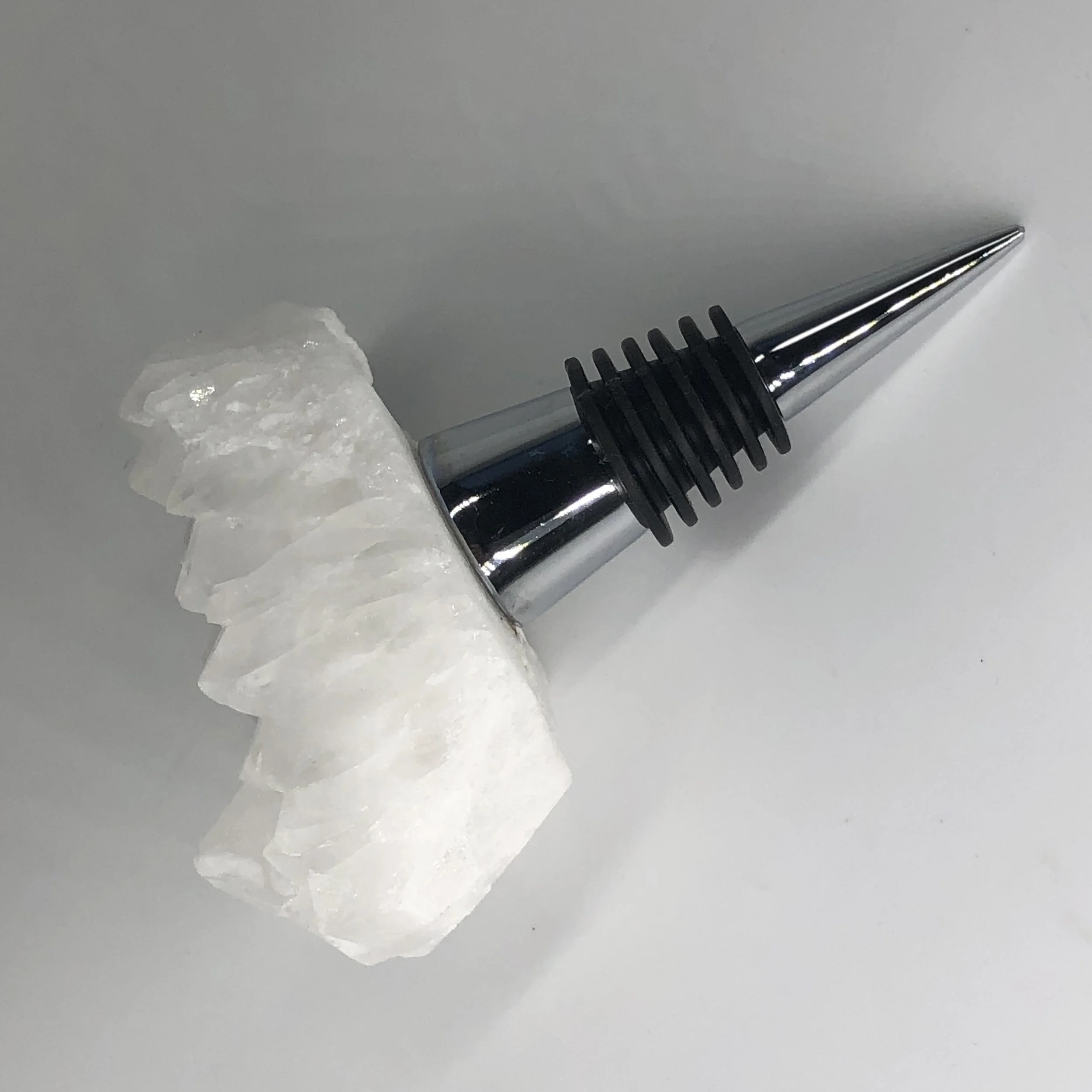 A close-up image of a metallic rhinoceros horn sculpture, lying on a white surface with a piece of crumpled plastic or tissue nearby.