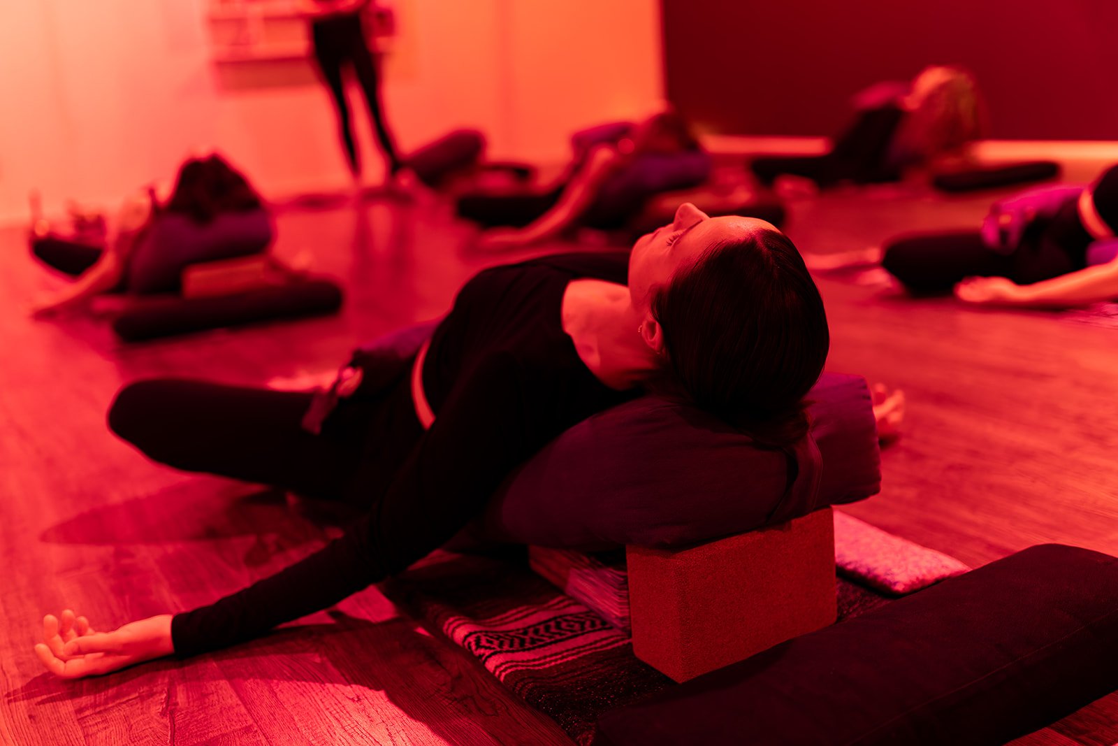 Person in yoga pose with legs crossed and resting on a bolster
