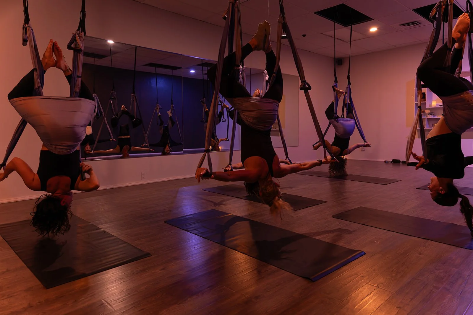 Person performing aerial yoga in a hammock, wearing black leggings and top.