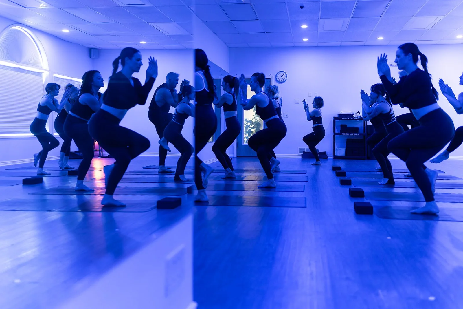 People practicing yoga in a studio, performing a balance pose on mats with yoga blocks.