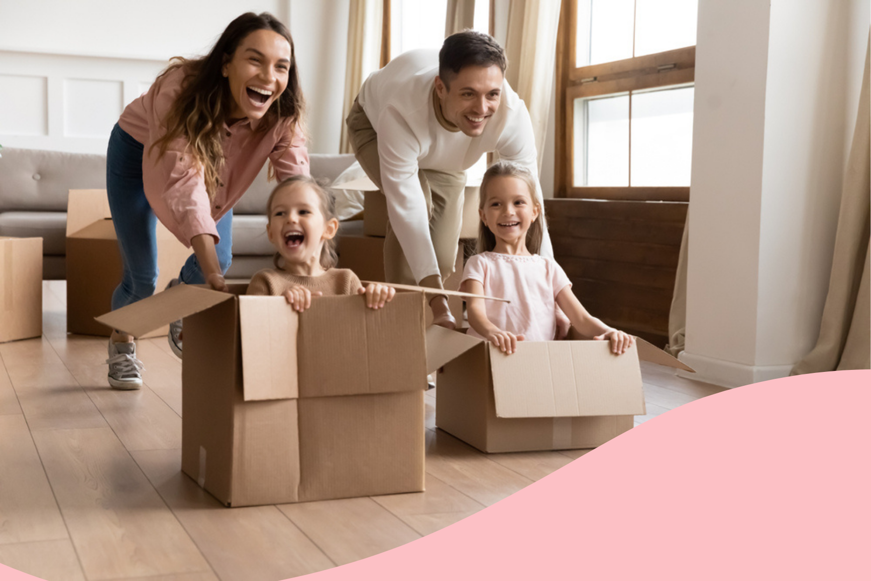 two smiling children in cardboard boxes being pushed by their smiling parents