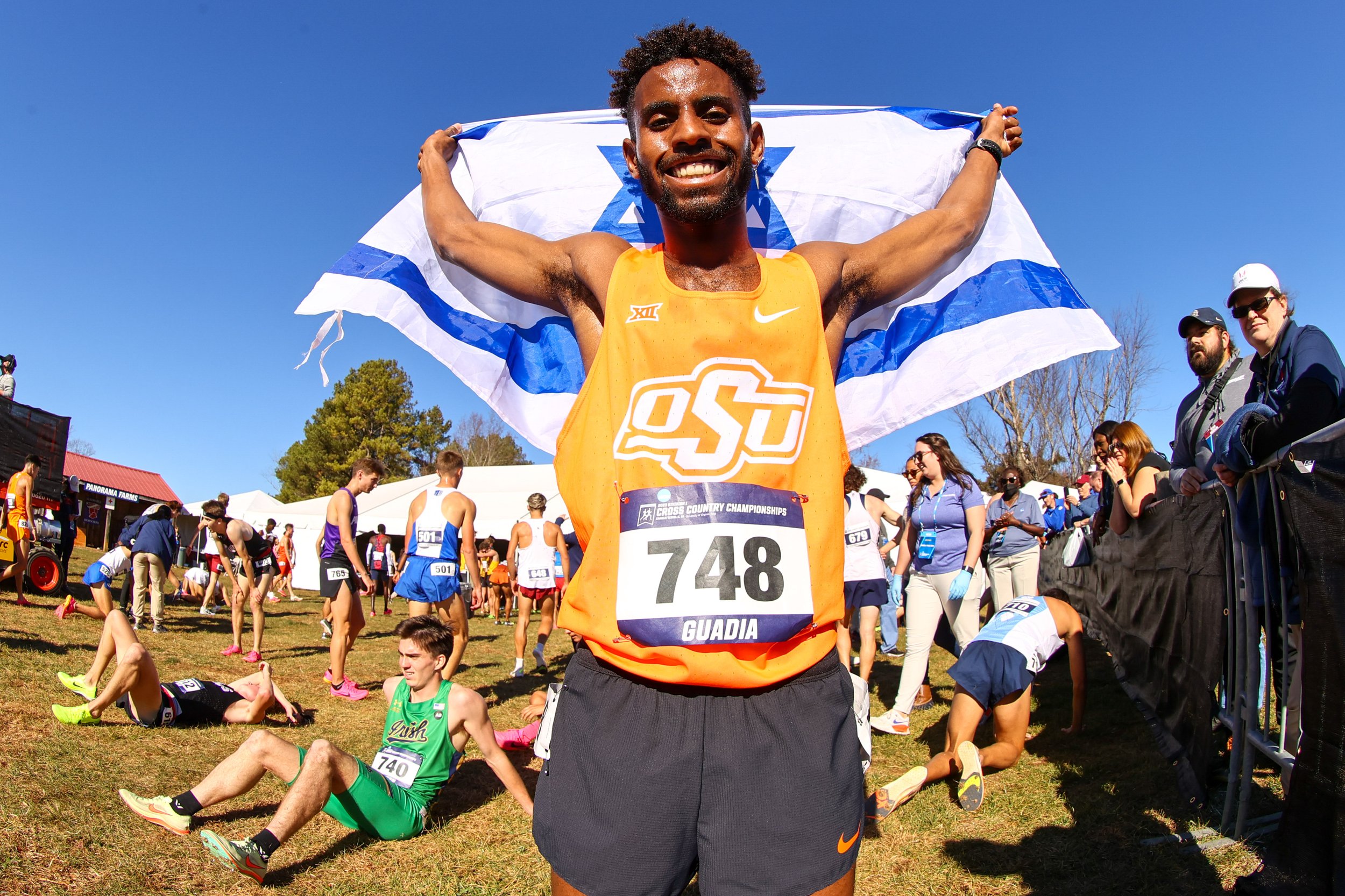  EARLYSVILLE, VIRGINIA - NOVEMBER 18: Adisu Guadia #748 of the Oklahoma State Cowboys holds up an Israeli flag in celebration during the Division I Men’s and Women’s Cross Country Championship held at Panorama Farms on November 18, 2023 in Earlysvill