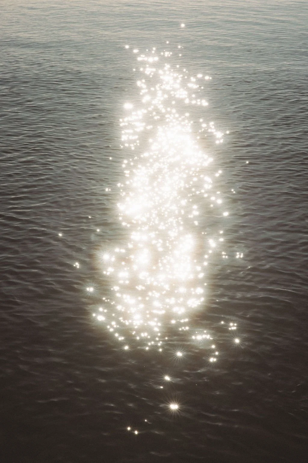 Gentle ripples across the ocean with the sun reflecting on the surface in a patter of beautiful golden sparkles