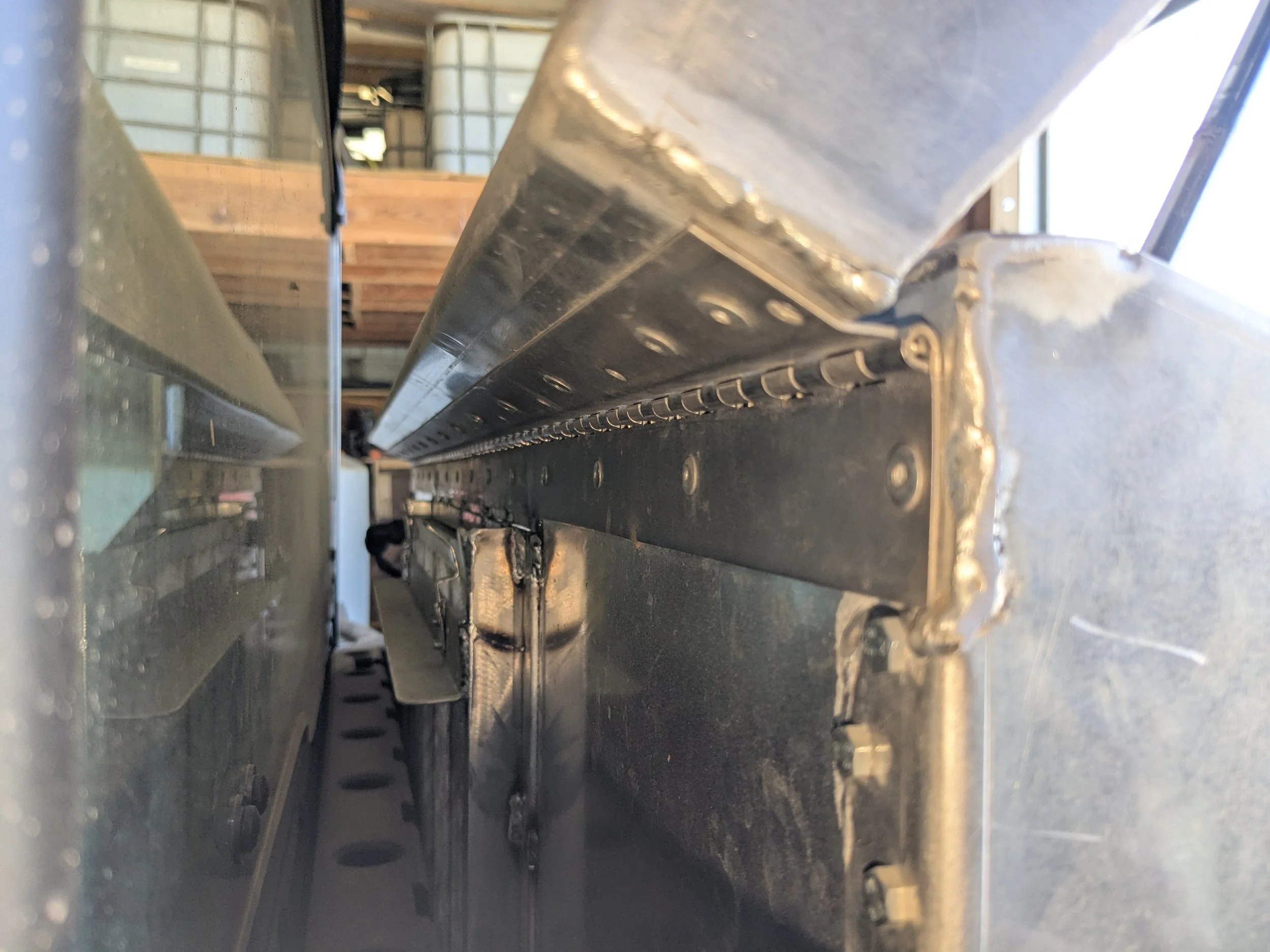 Close-up of metal construction, showing a riveted metal beam and a long metal rail in an industrial or warehouse setting.