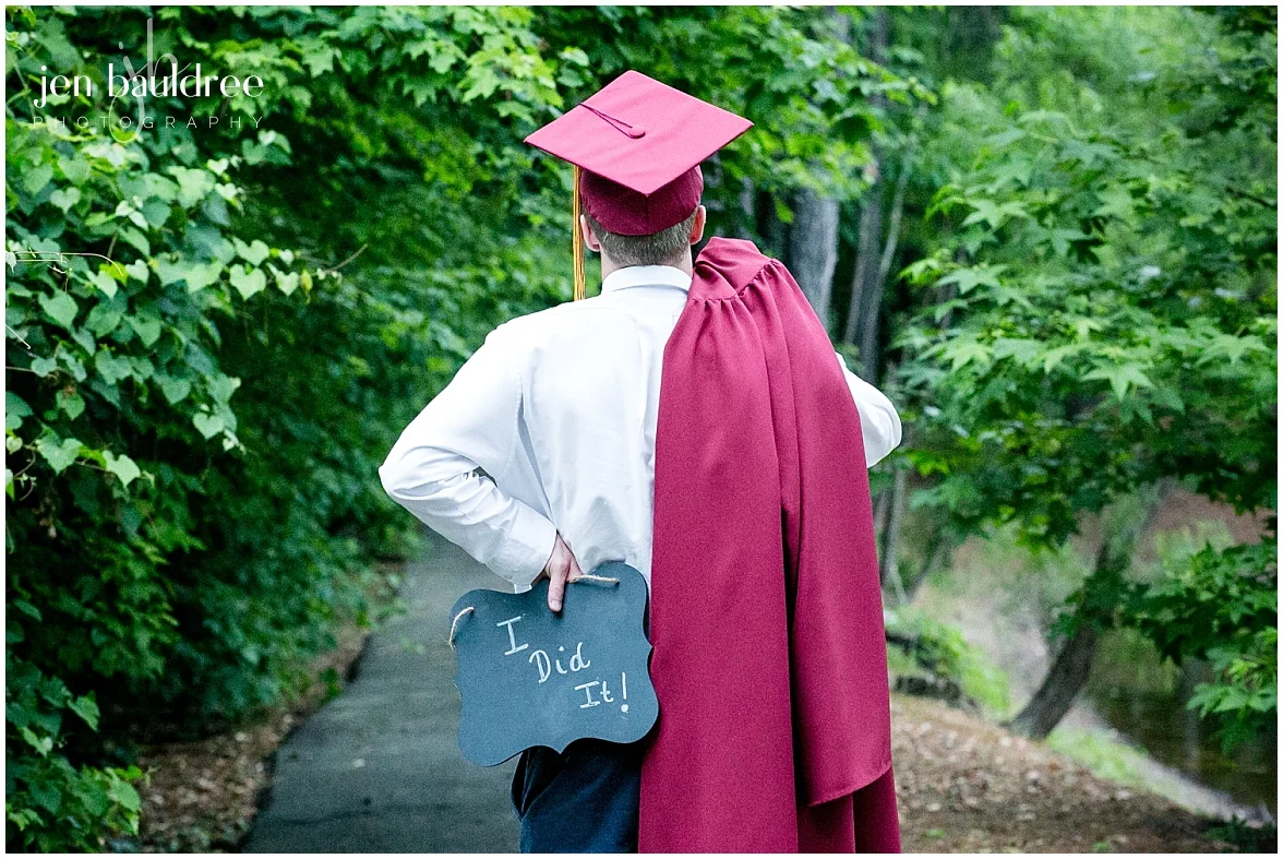 senior guy in cap & gown holding I did it sign.jpg