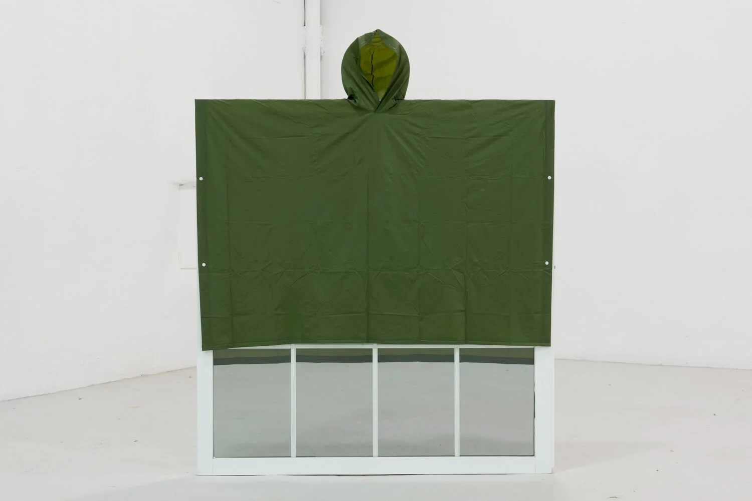“Lo necesario puede ser tan arbitrario como caprichos tengamos”, 2017. Capa de lluvia sobre ventana. Foto cortesía de L21 Gallery