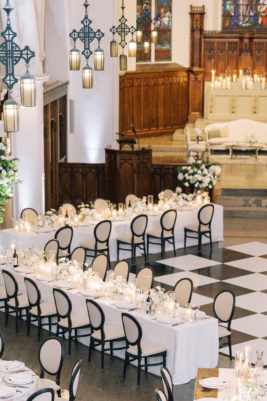 Elegant wedding reception setup inside The Abbey with dining tables and a black and white dance floor.