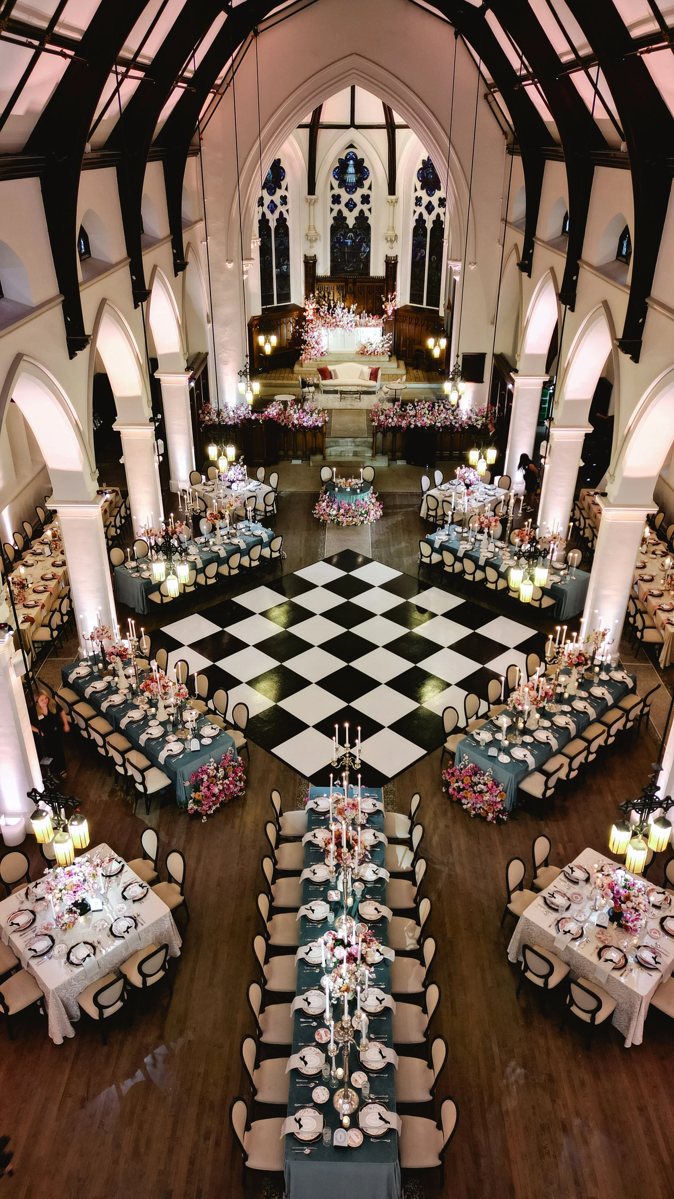 The Abbey wedding reception space featuring a black and white dance floor, floral arrangements, candlelight, and lounge seating.