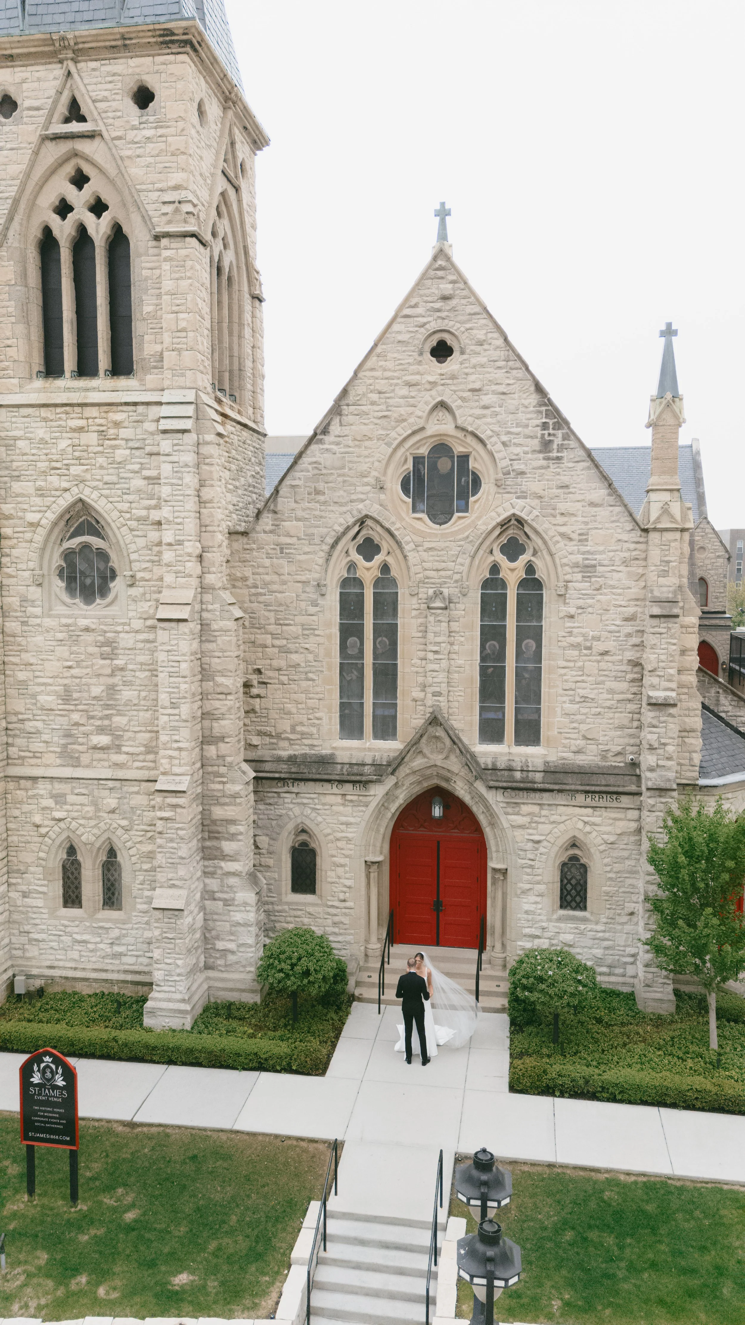 Newlywed couple embracing in front of the iconic red doors at St. James 1868 in Milwaukee.