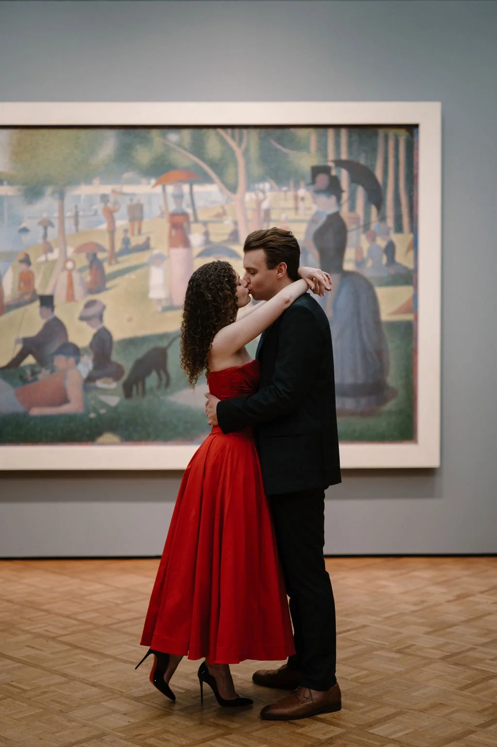 Chicago engagement photos of a couple kissing in front of Seurat's A Sunday on La Grande Jatte at the Art Institute of Chicago