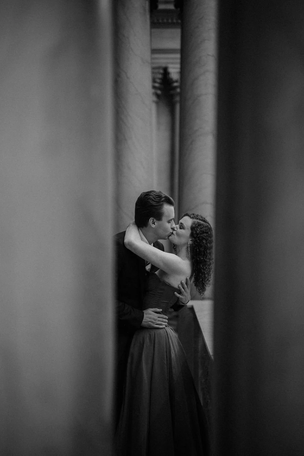 Chicago engagement photos in black and white, with a couple kissing between two marble columns at the Art Institute
