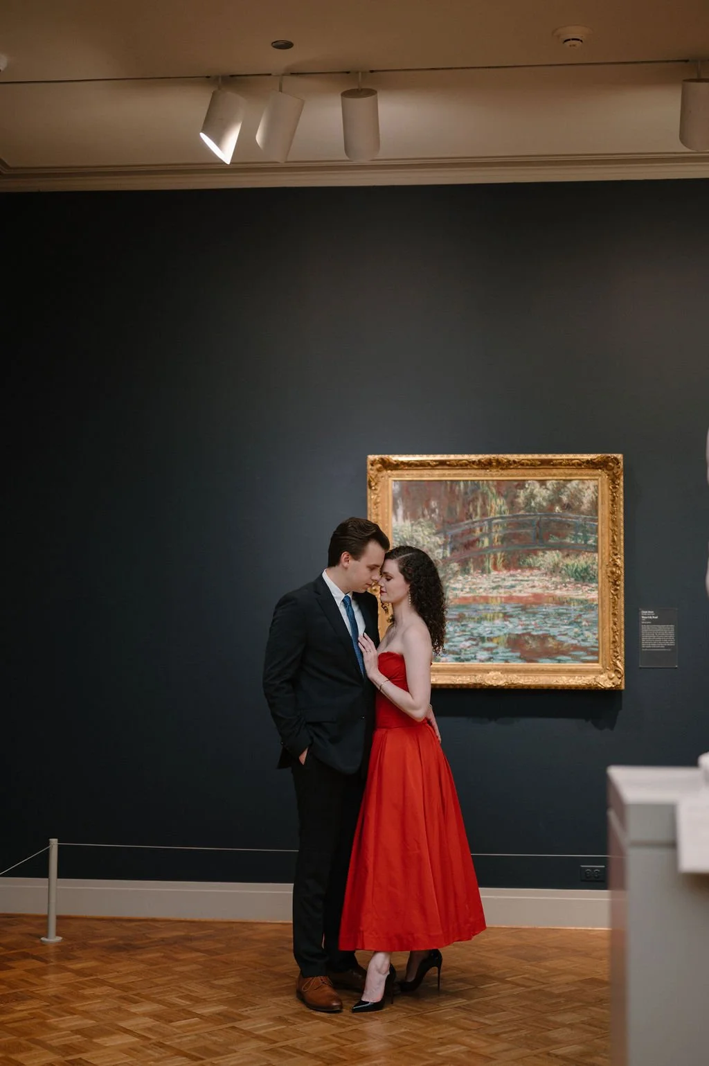 Couple embracing in front of Monet's Water Lily Pond in an Art Institute of Chicago gallery, she in a red dress