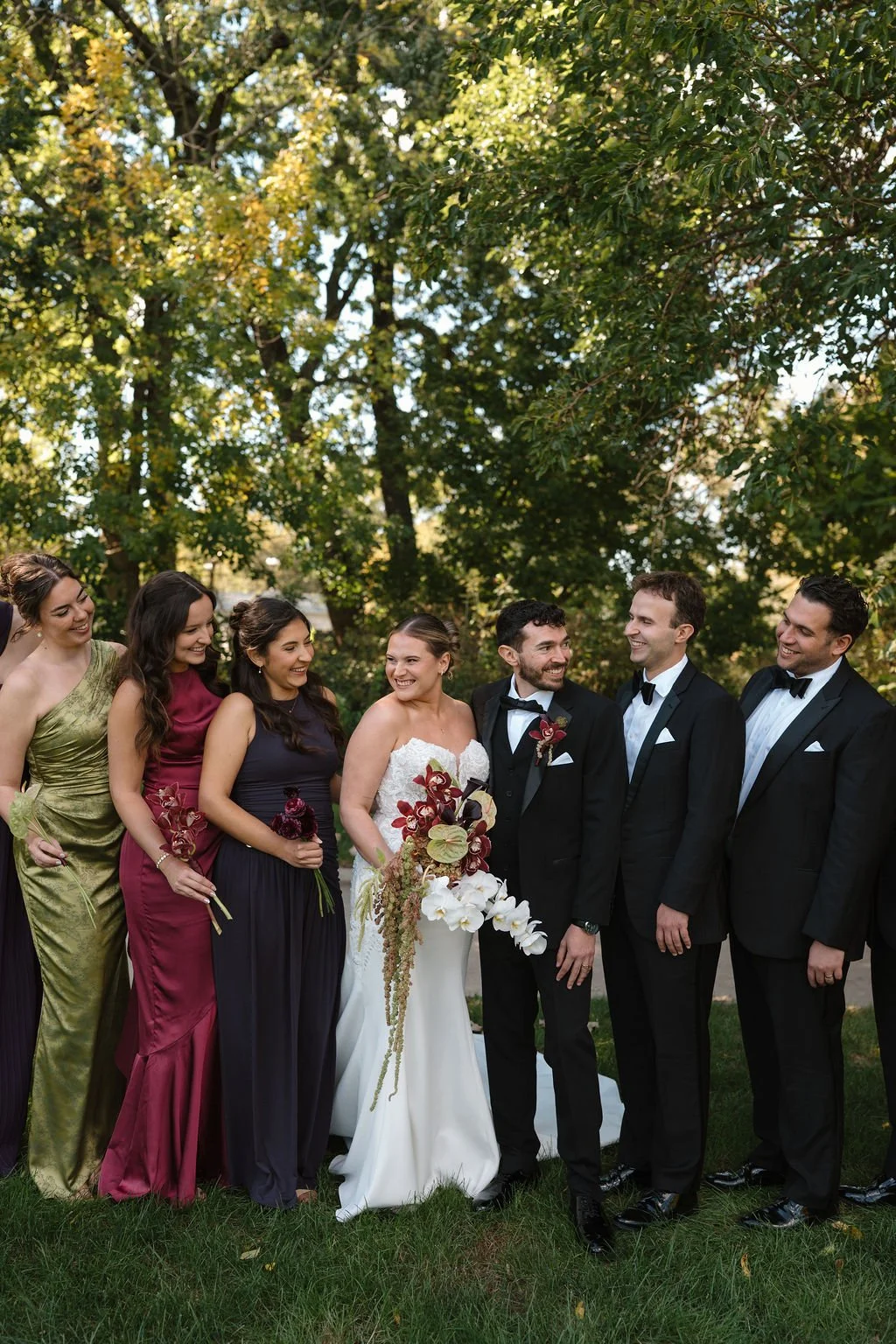 Bride and groom laughing with their bridal party in a park before heading to one of the Fort Wayne wedding venues for the reception