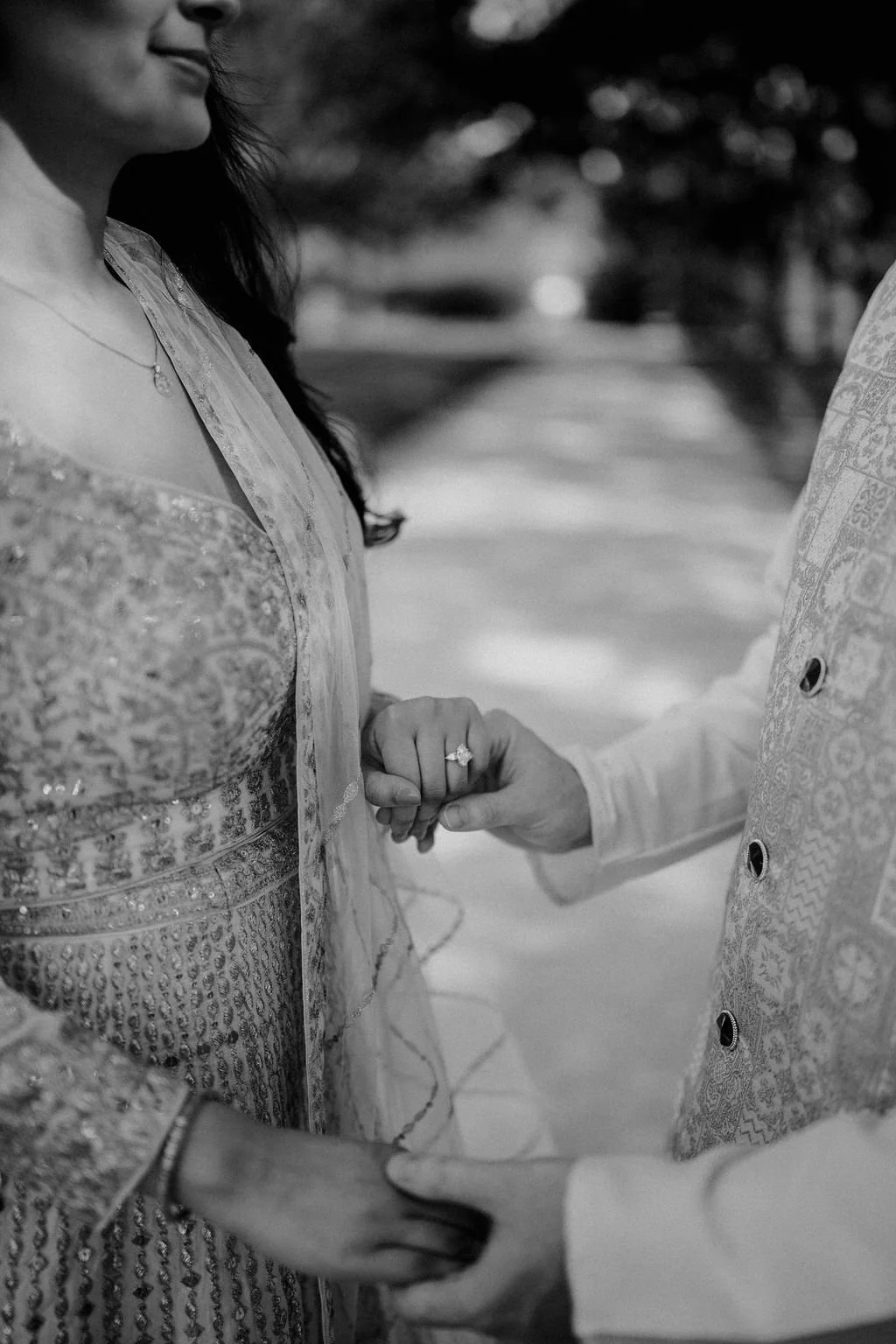 Engagement photo ideas that focus on the details, with a close up in black and white of a couple holding hands and a sparkling engagement ring.