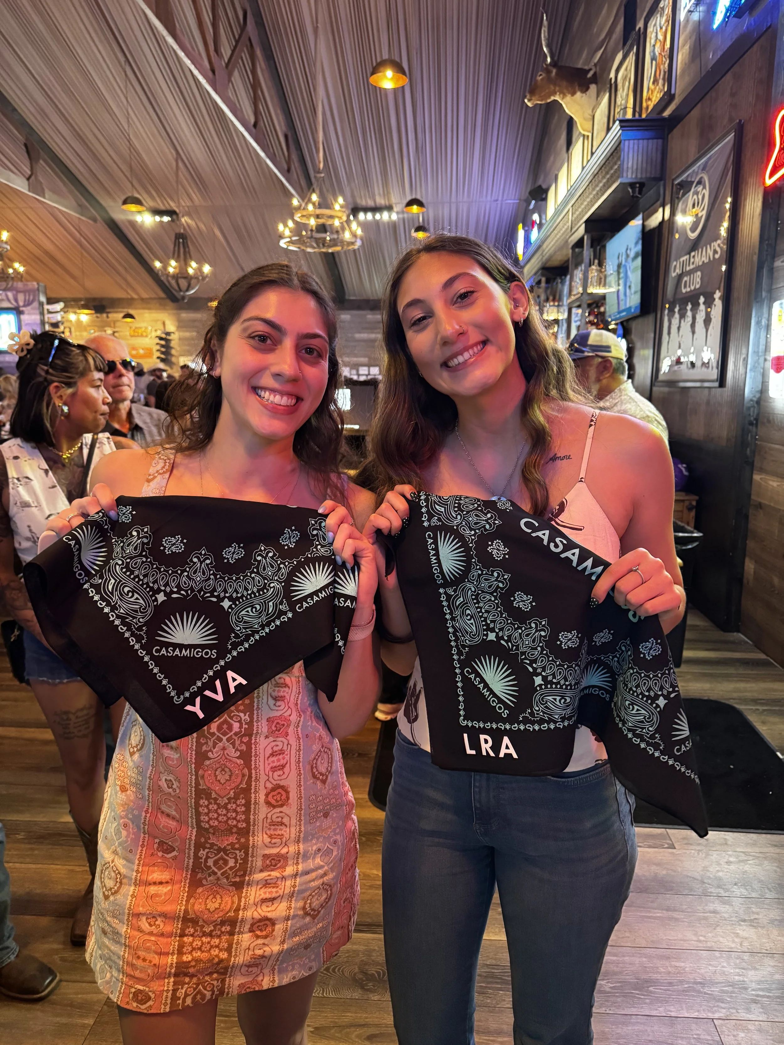 Two guests of Cattleman's Club display their freshly heat pressed and monogrammed bandana's with their initials and casamigos branding