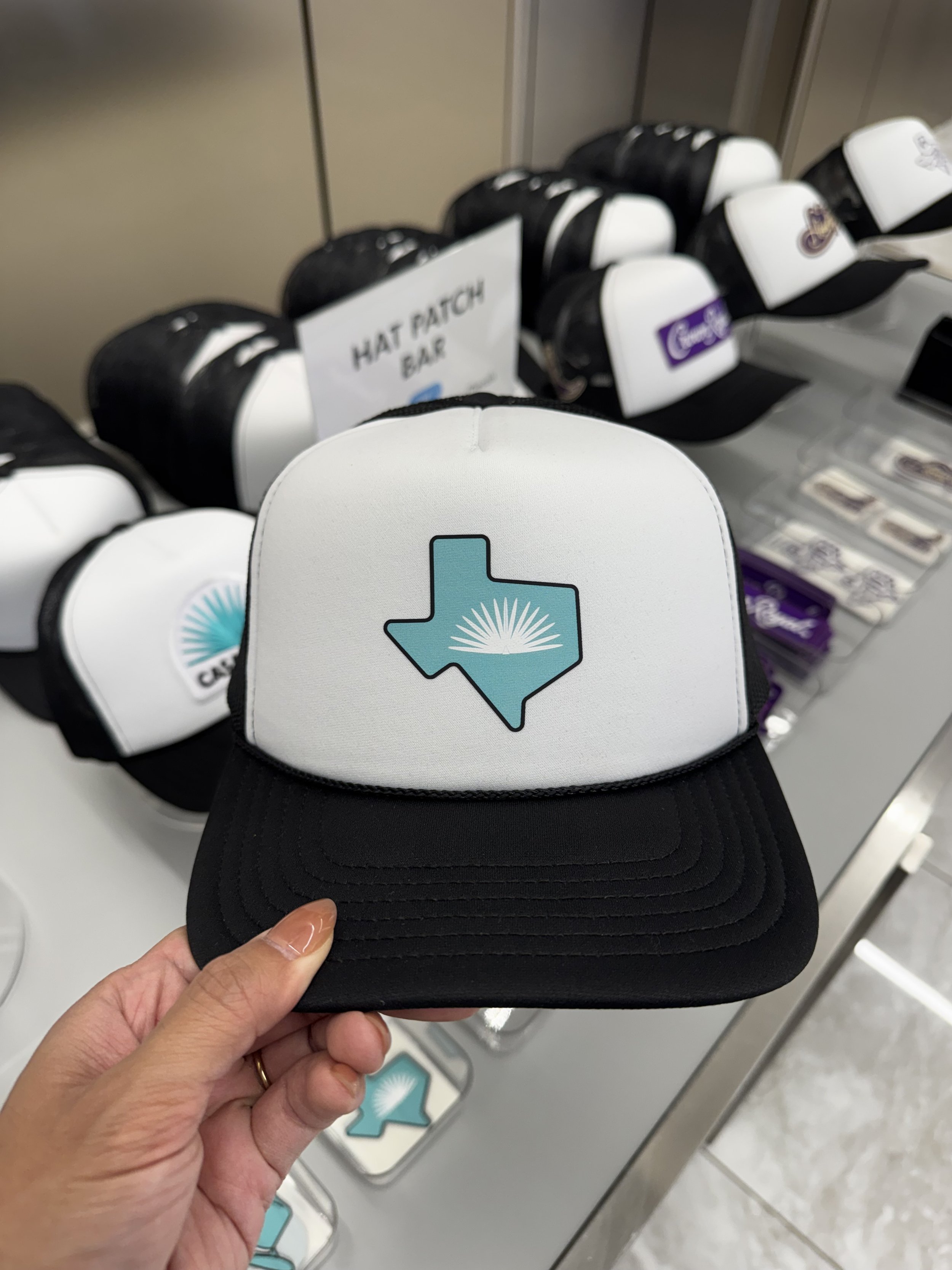 Casamigos agave logo inside of turquoise Texas shape heat pressed onto black and white trucker hat.