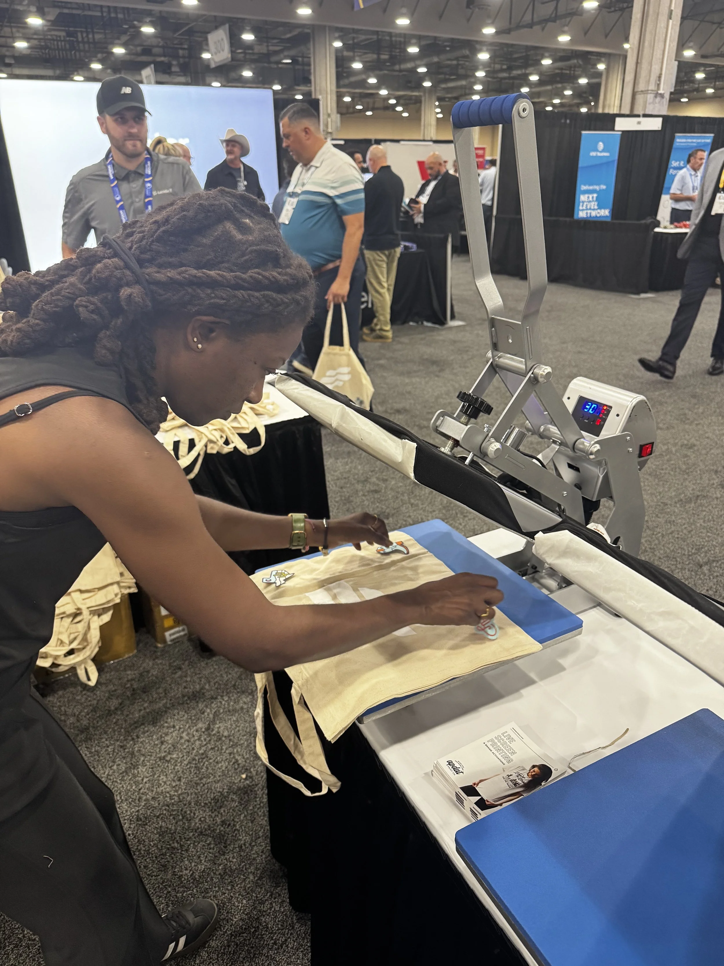 Apdat staff laying out patches carefully on the press before applying heat and permenantly adhering the patches to the tote bag